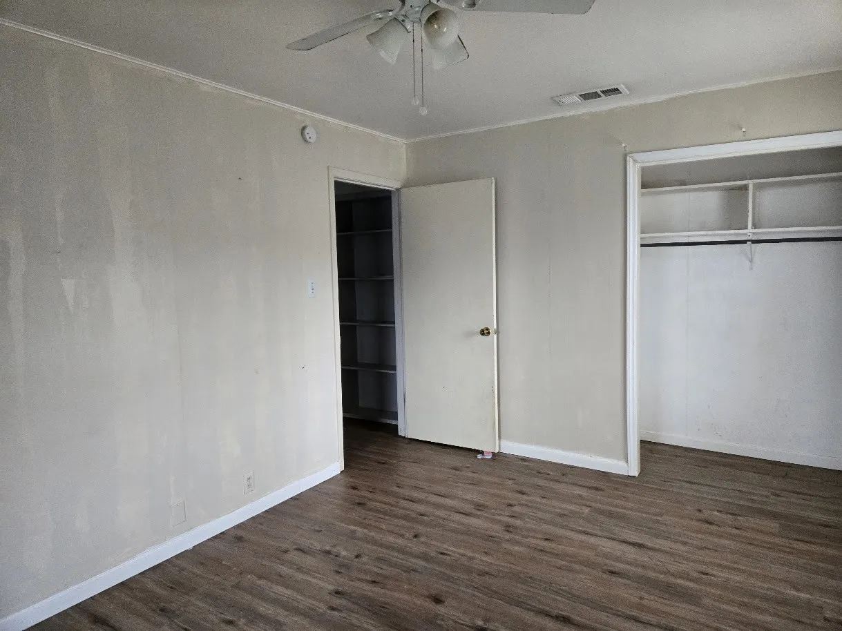 Unfurnished bedroom featuring dark wood-style floors, a closet, ceiling fan, and ornamental molding