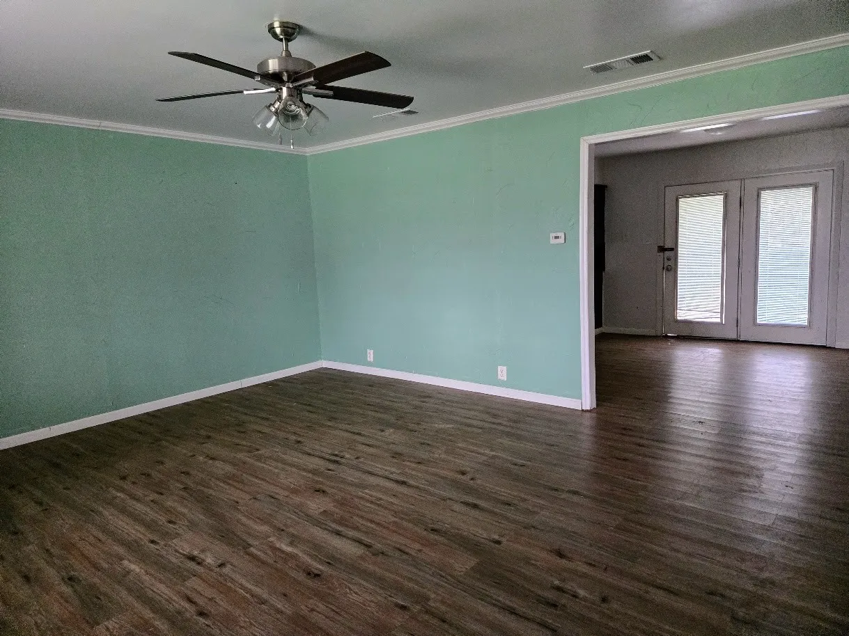 Spare room featuring a ceiling fan, ornamental molding, and dark wood-style flooring