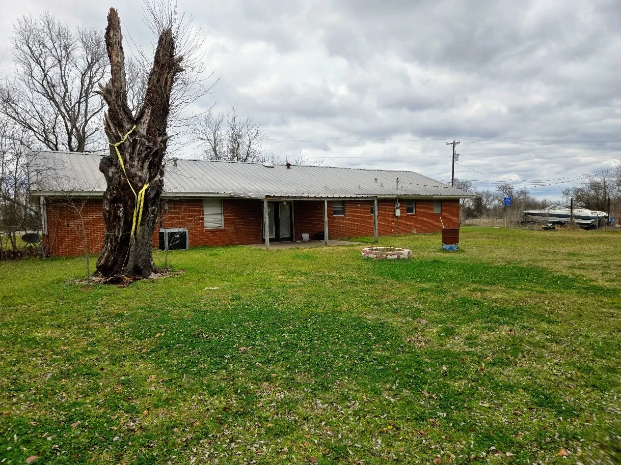 Back of house with a patio, a lawn, and a metal roof