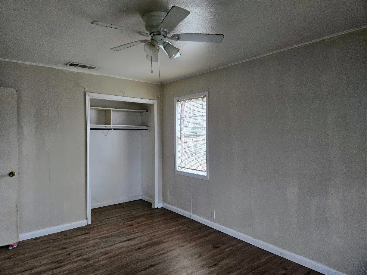 Unfurnished bedroom featuring dark wood-style flooring, a closet, ceiling fan, and a textured ceiling