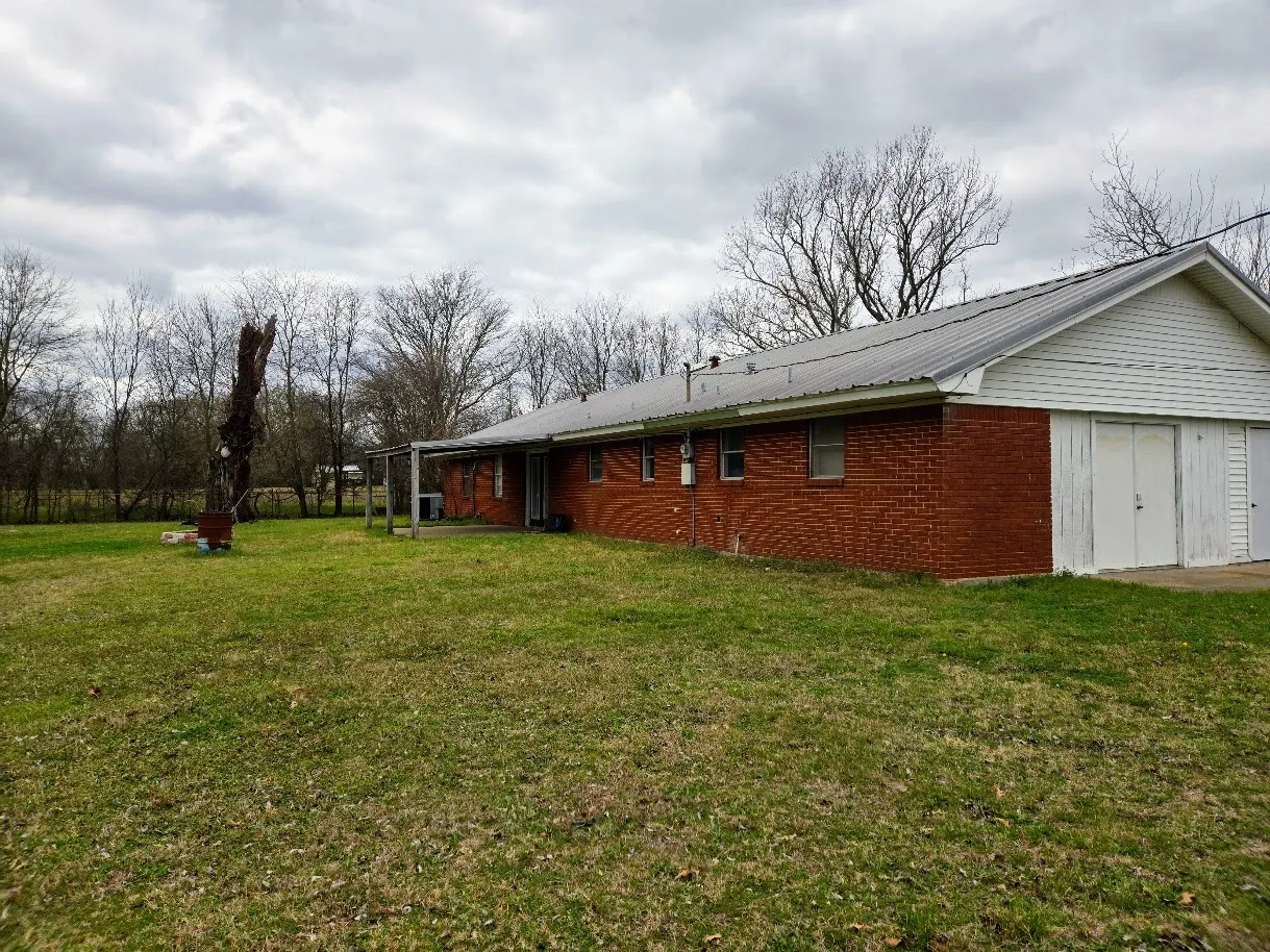 View of side of property featuring a yard and a metal roof