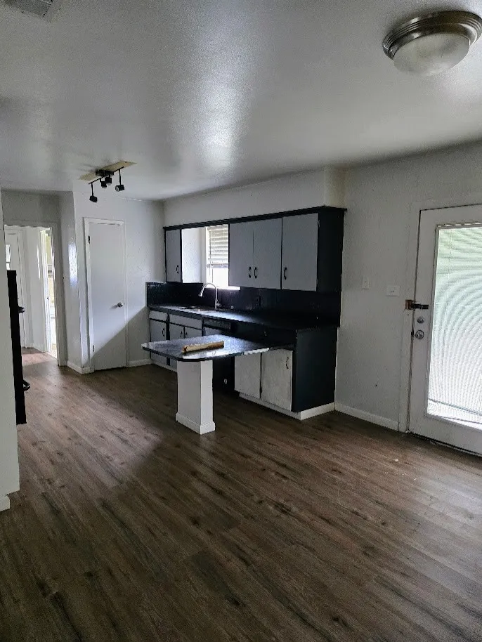 Kitchen with dark countertops, a peninsula, a kitchen breakfast bar, dark wood finished floors, and a textured ceiling