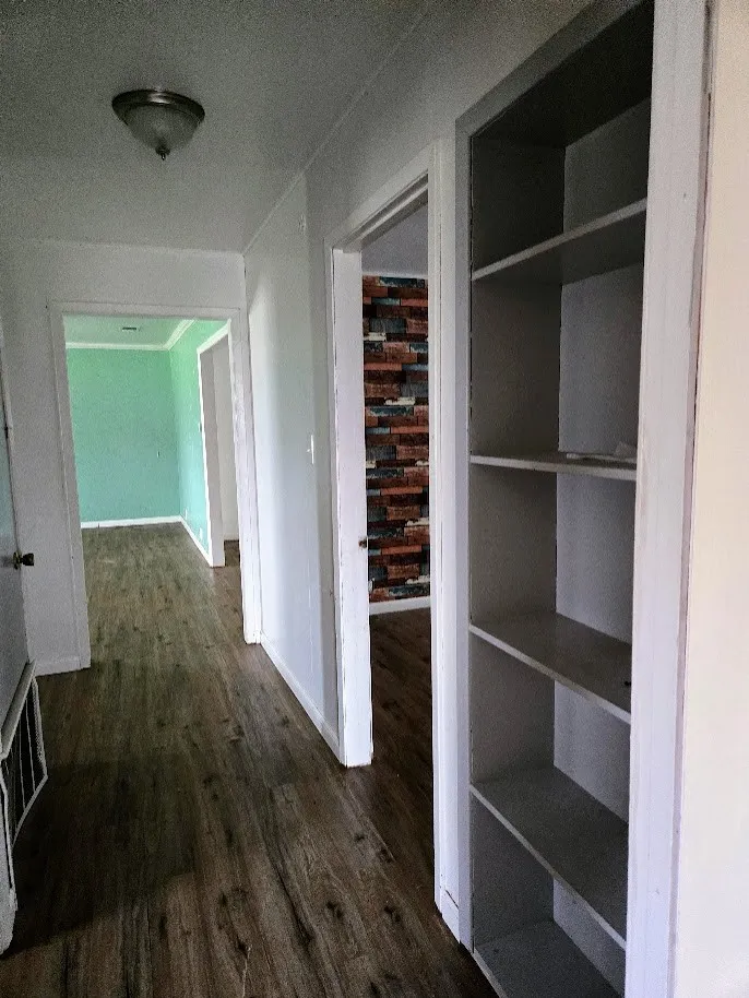 Hallway featuring dark wood-style floors and baseboards