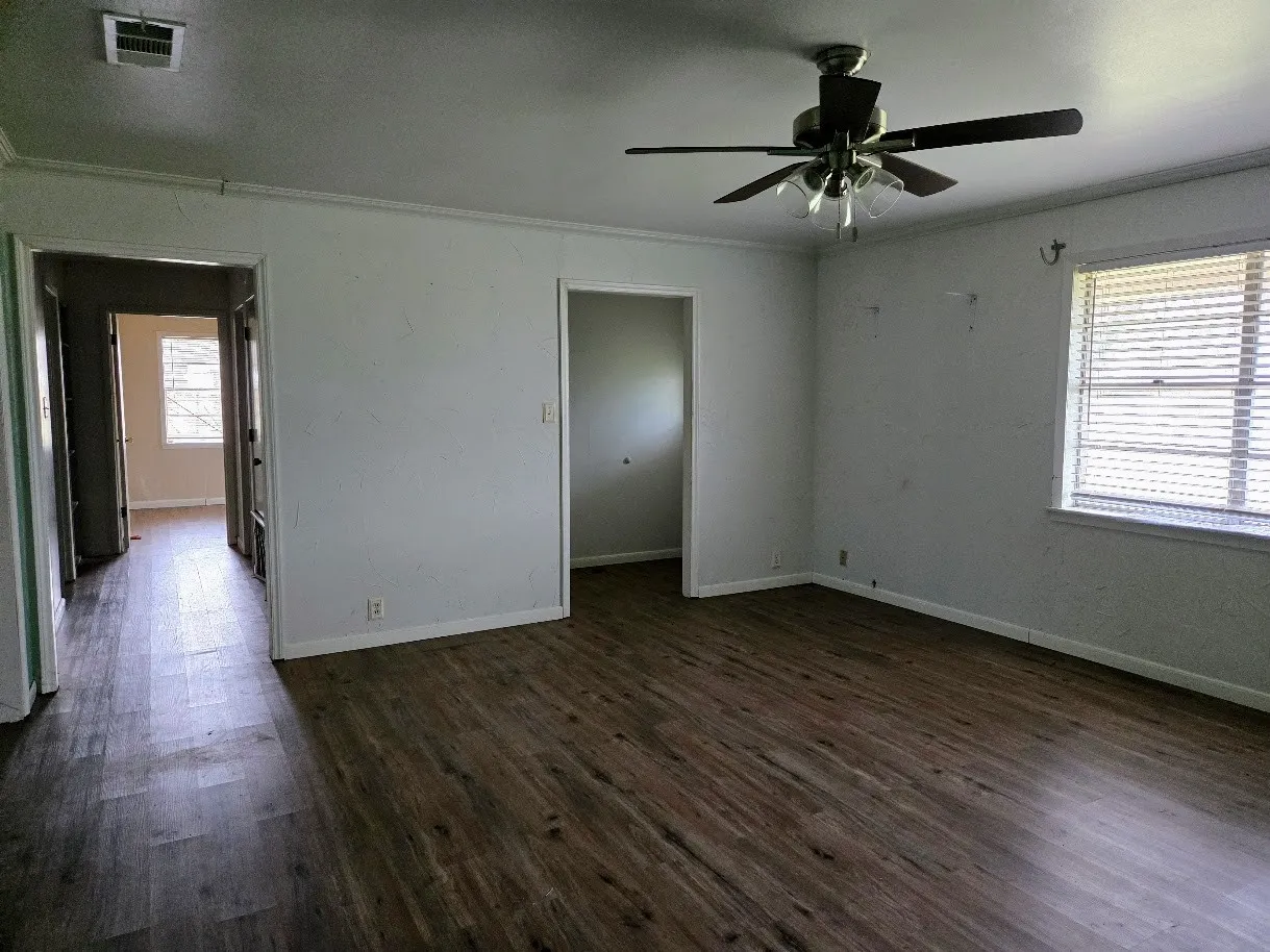 Spare room featuring dark wood-type flooring, ceiling fan, and crown molding
