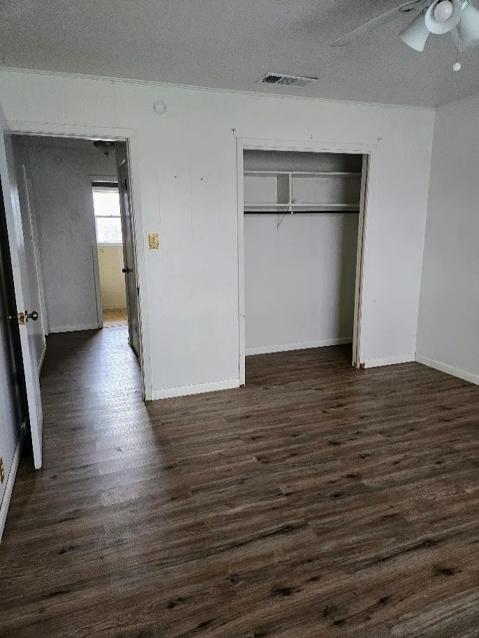 Unfurnished bedroom with a textured ceiling, dark wood-style floors, a closet, and a ceiling fan