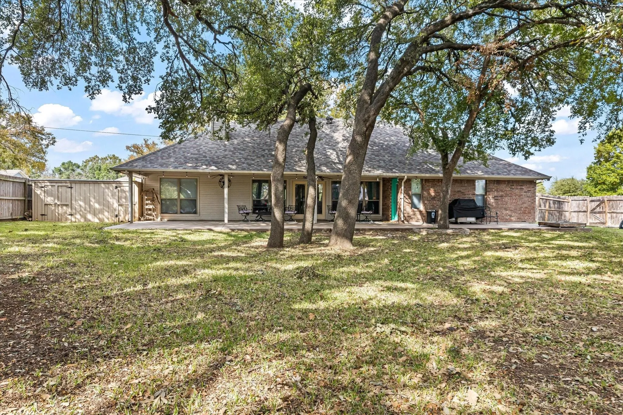 Back of house featuring a yard, a fenced backyard, a patio, roof with shingles, and brick siding
