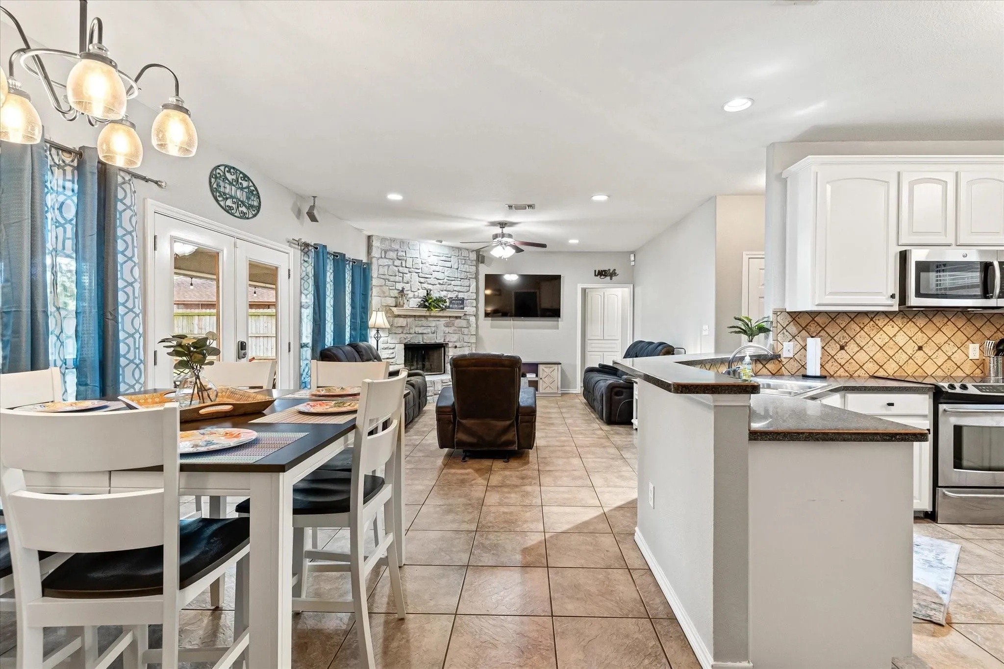Kitchen featuring a ceiling fan, a sink, dark countertops, stainless steel appliances, and backsplash