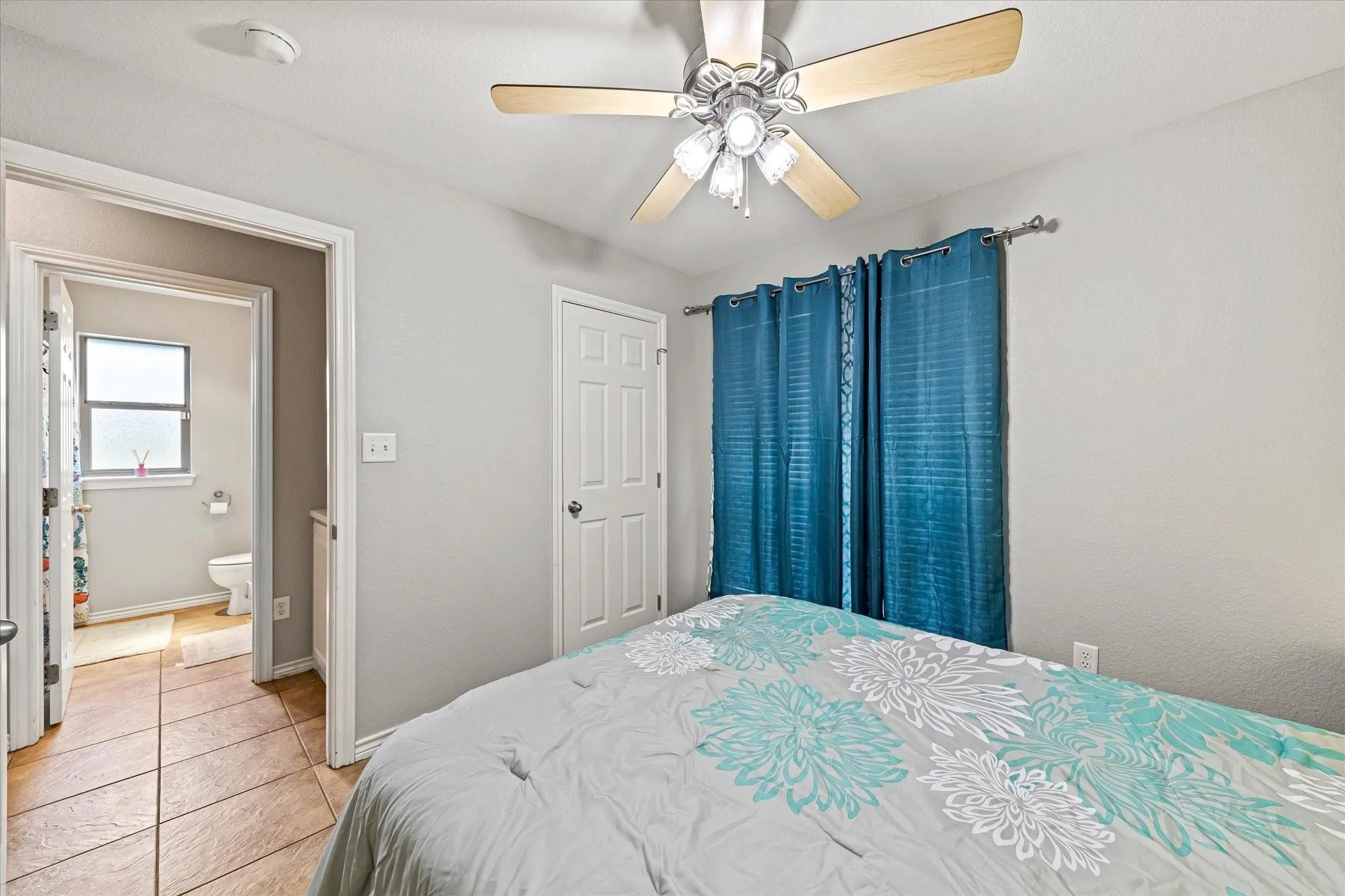 Bedroom with light tile patterned floors, baseboards, and a ceiling fan