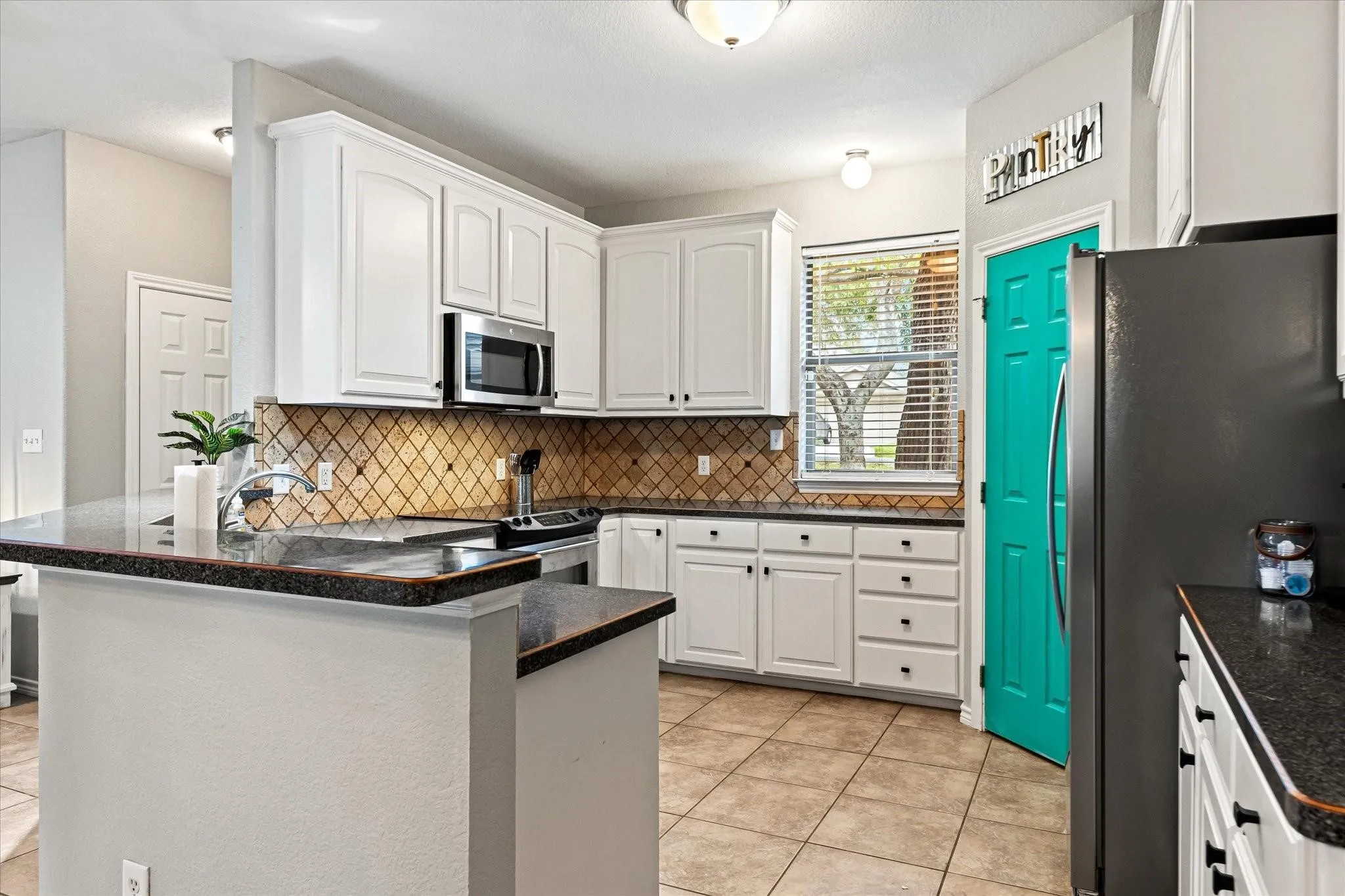 Kitchen featuring white cabinets, a peninsula, light tile patterned floors, and appliances with stainless steel finishes