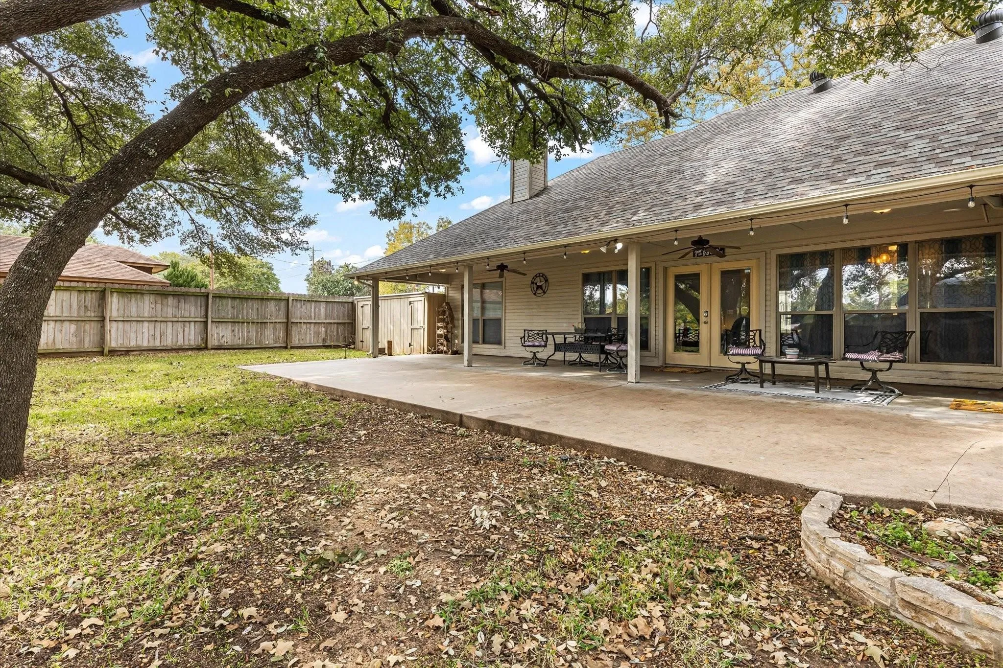 Rear view of property featuring a fenced backyard, a chimney, a patio, french doors, and a shingled roof