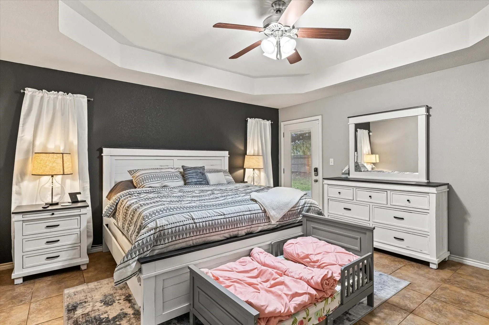 Bedroom with a tray ceiling, a ceiling fan, access to exterior, light tile patterned flooring, and baseboards
