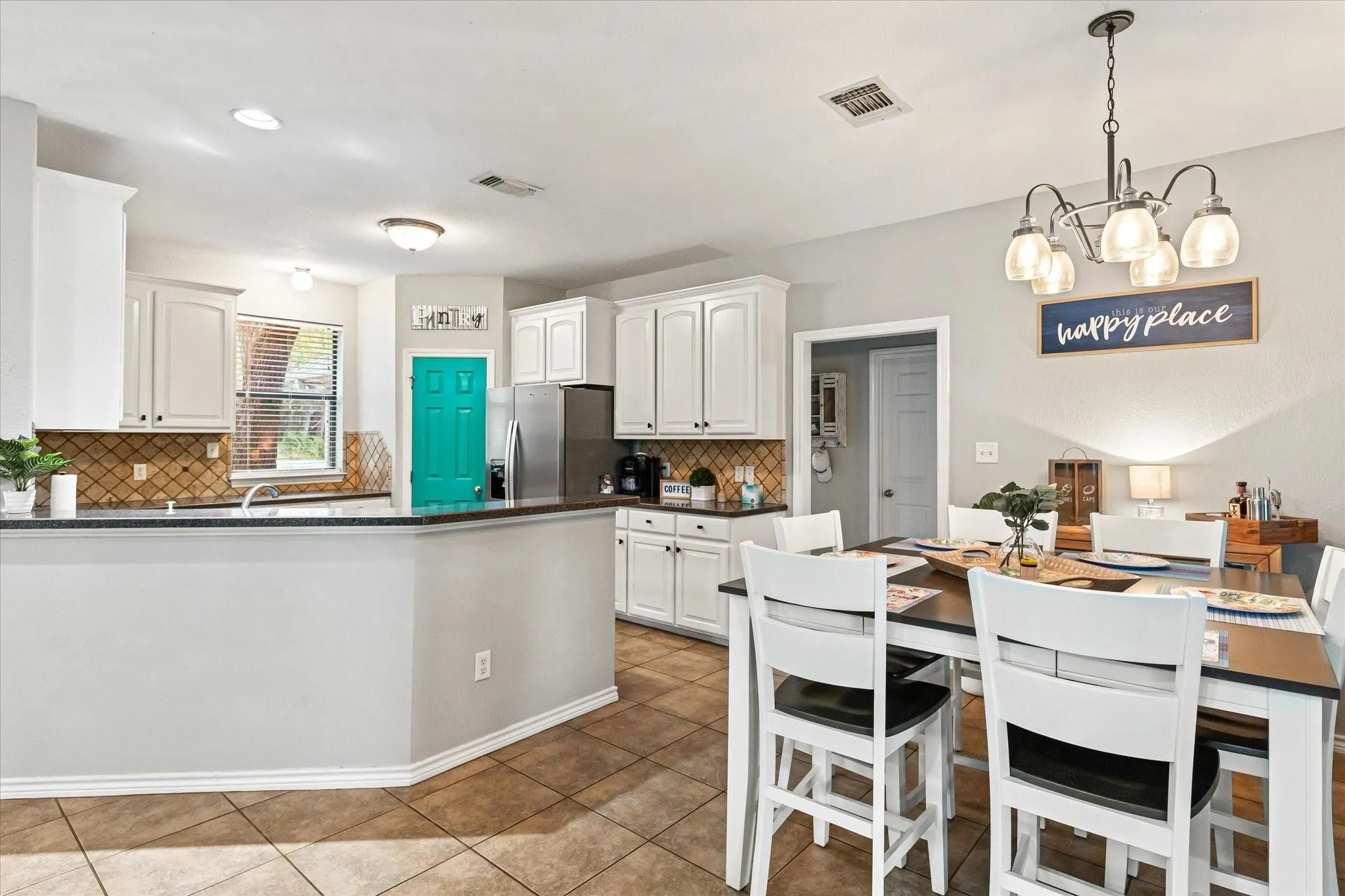 Kitchen with visible vents, dark countertops, and stainless steel refrigerator with ice dispenser