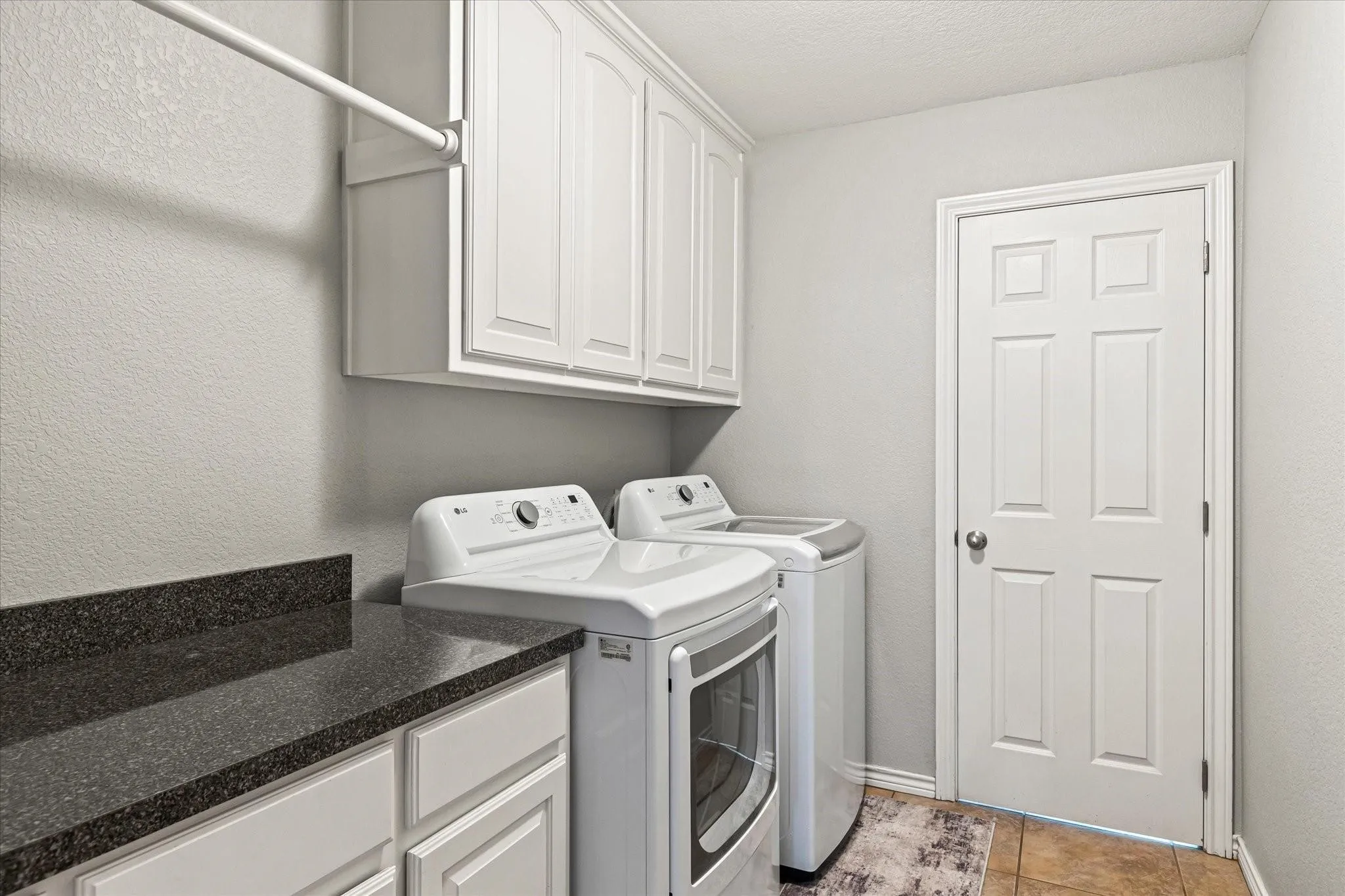 Washroom with washer and dryer, light tile patterned floors, baseboards, and cabinet space