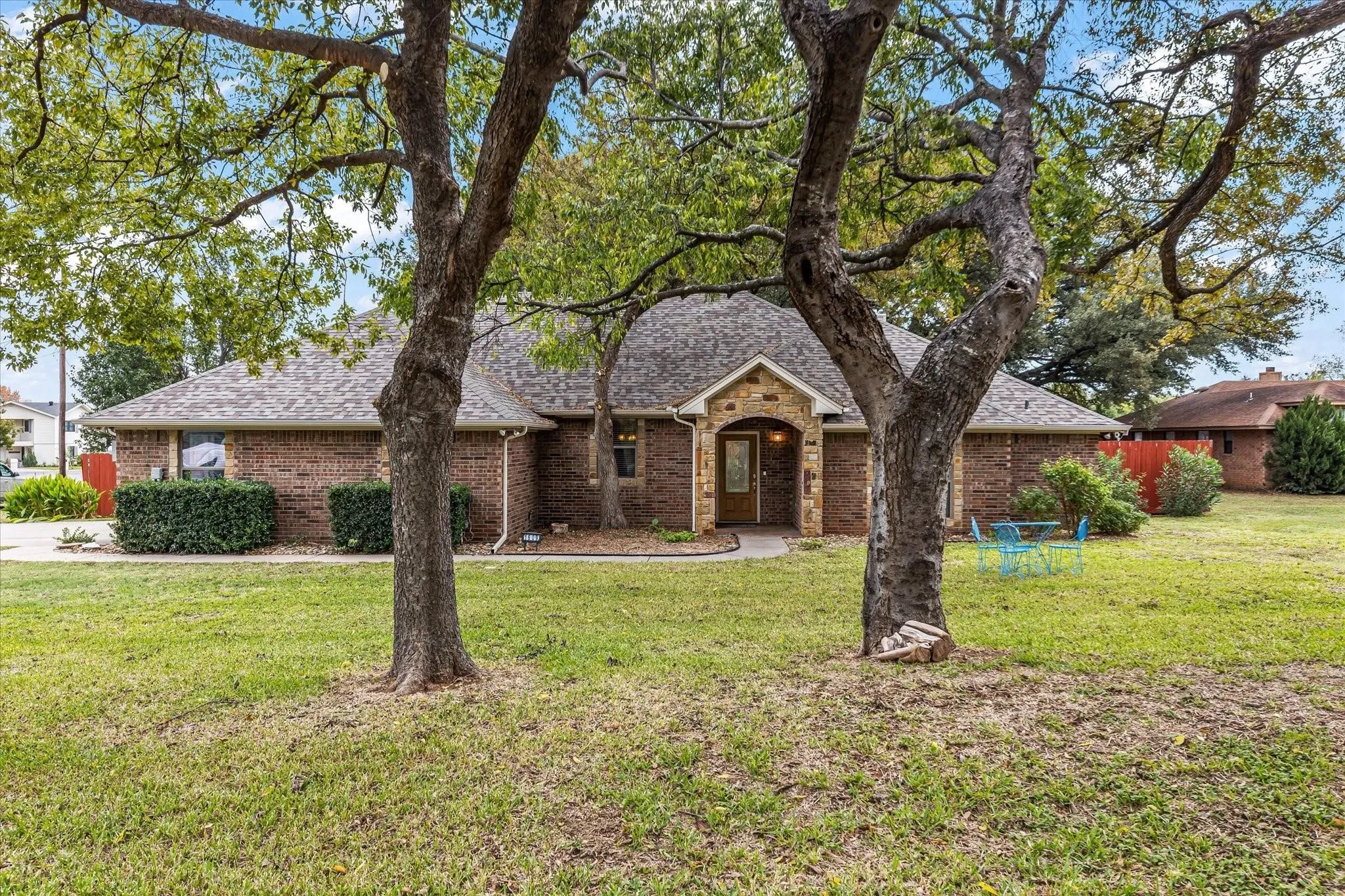 View of front of home featuring roof with shingles, brick siding, and a front yard