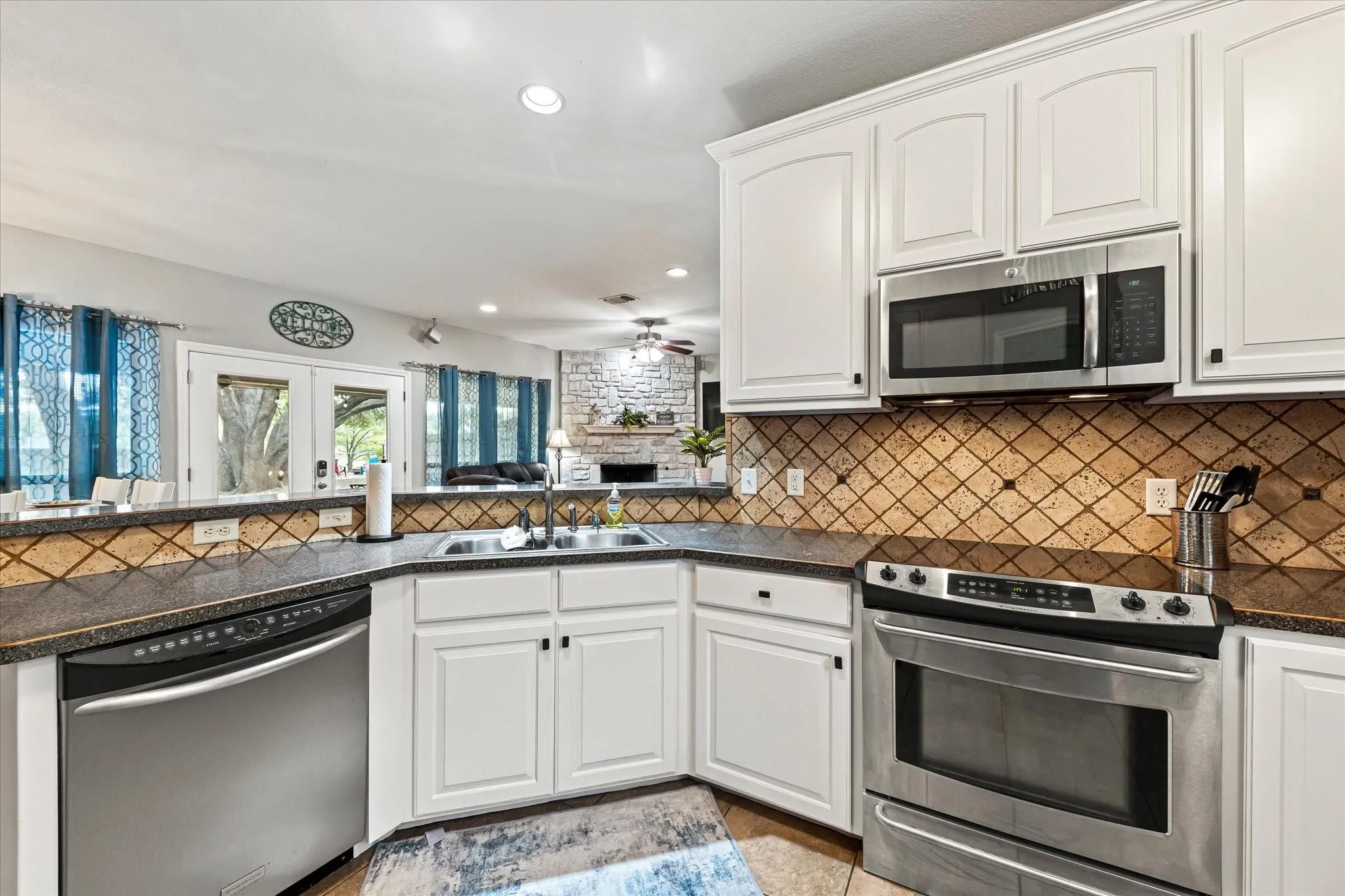 Kitchen featuring dark countertops, a sink, backsplash, and appliances with stainless steel finishes