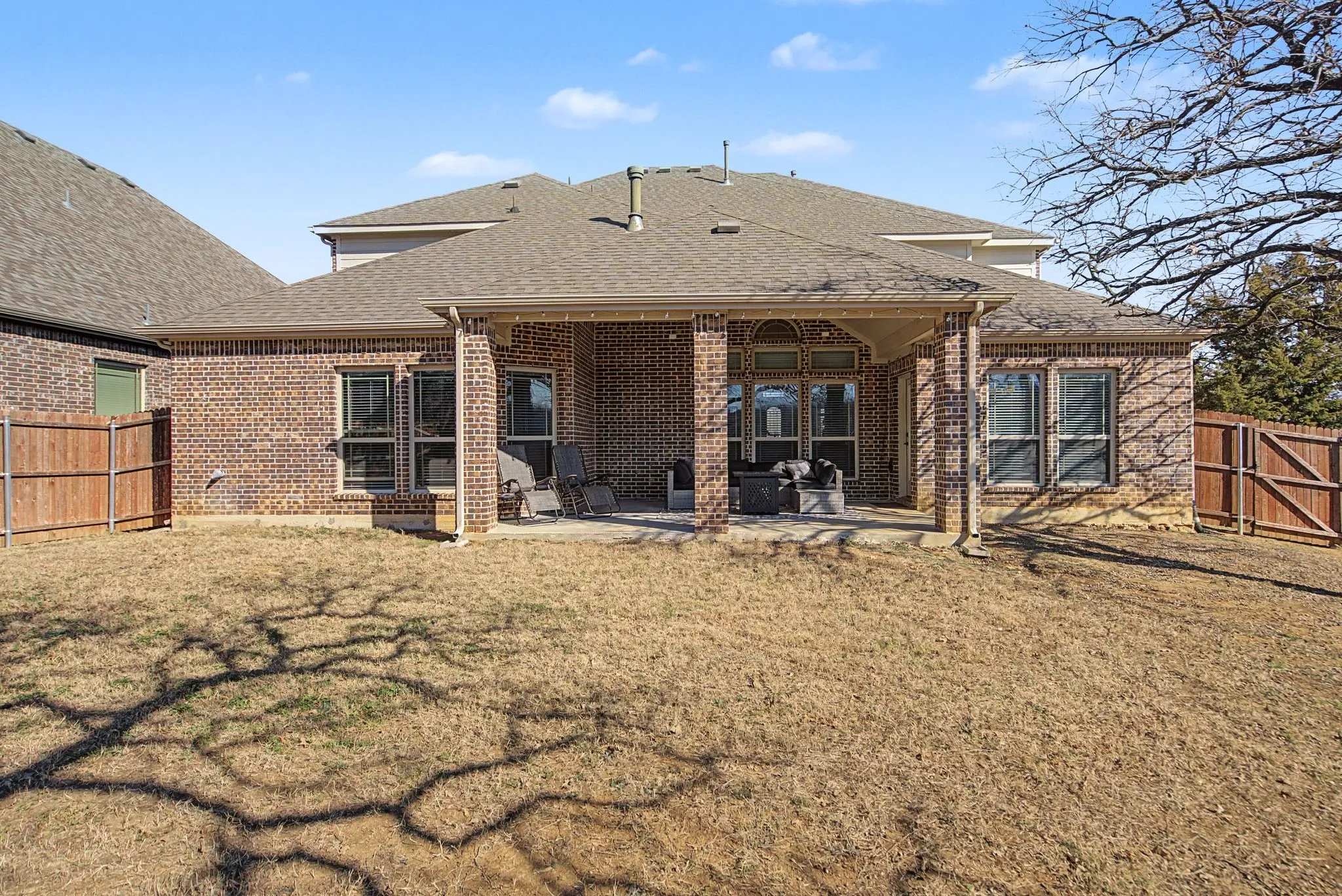 Rear view of house with a gate, roof with shingles, a fenced backyard, and a patio area