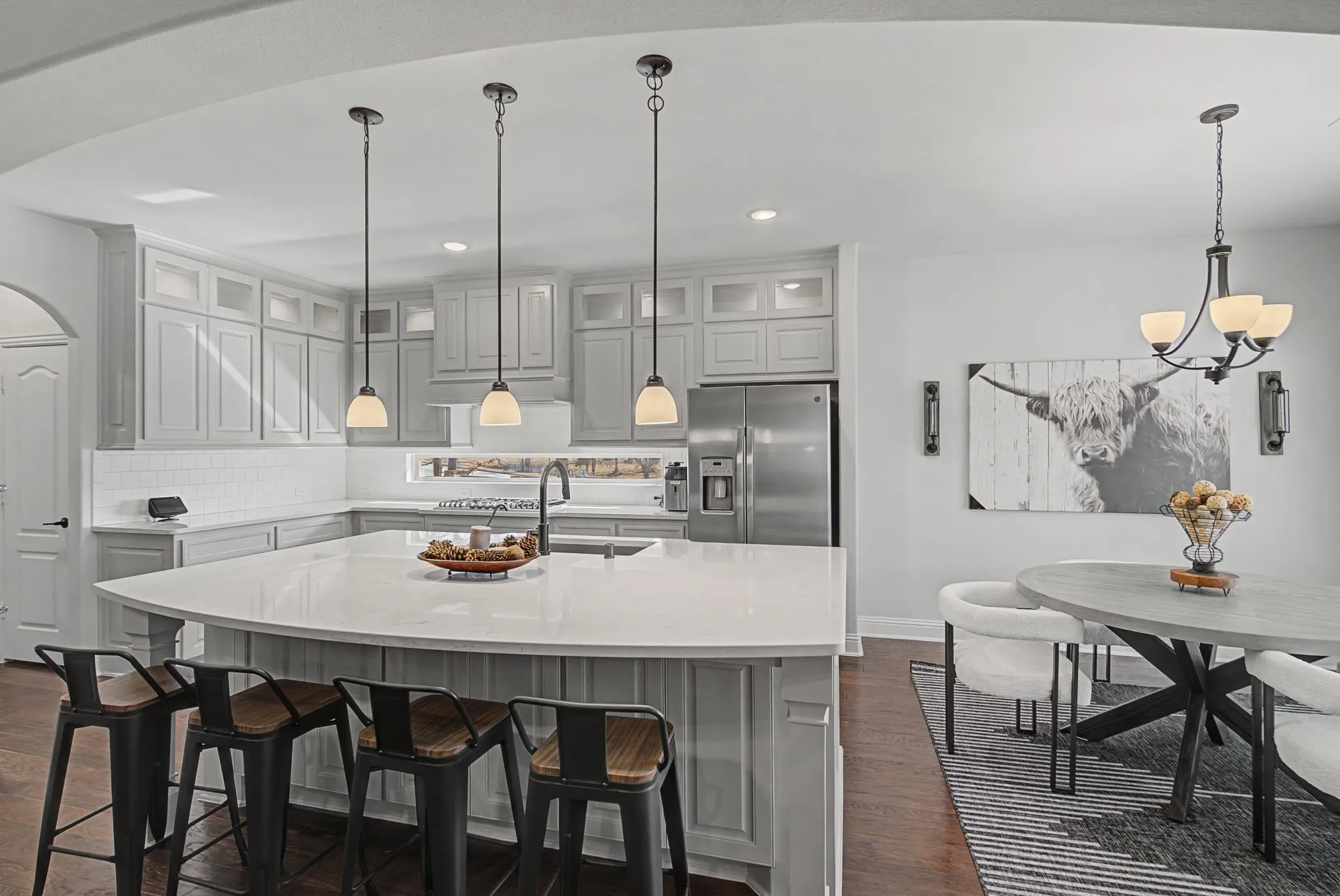Kitchen with glass fronted cabinets, arched walkways, and gray cabinets