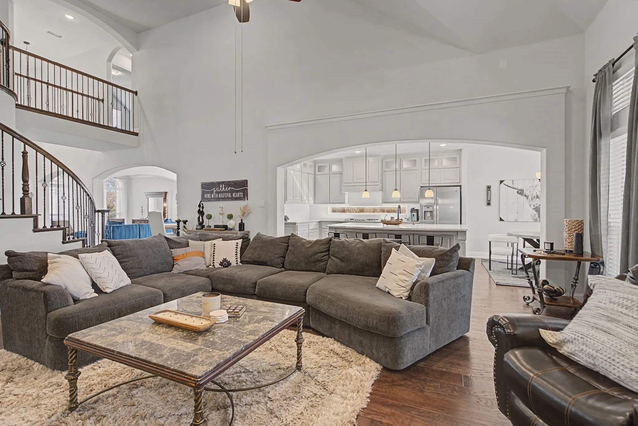 Living room featuring arched walkways, a ceiling fan, dark wood-style floors, and vaulted ceiling