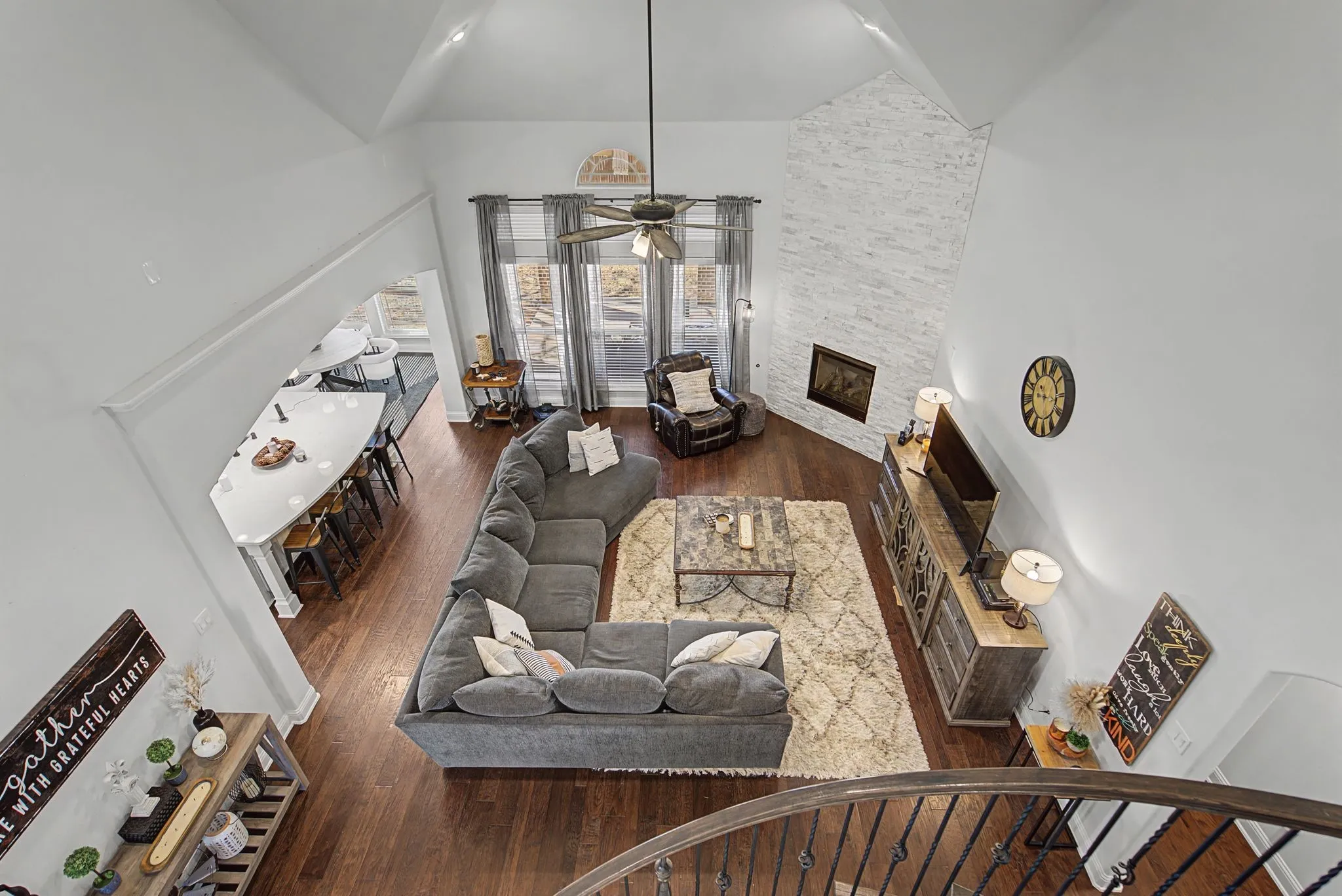 Living room featuring a fireplace, dark wood-type flooring, a ceiling fan, and vaulted ceiling