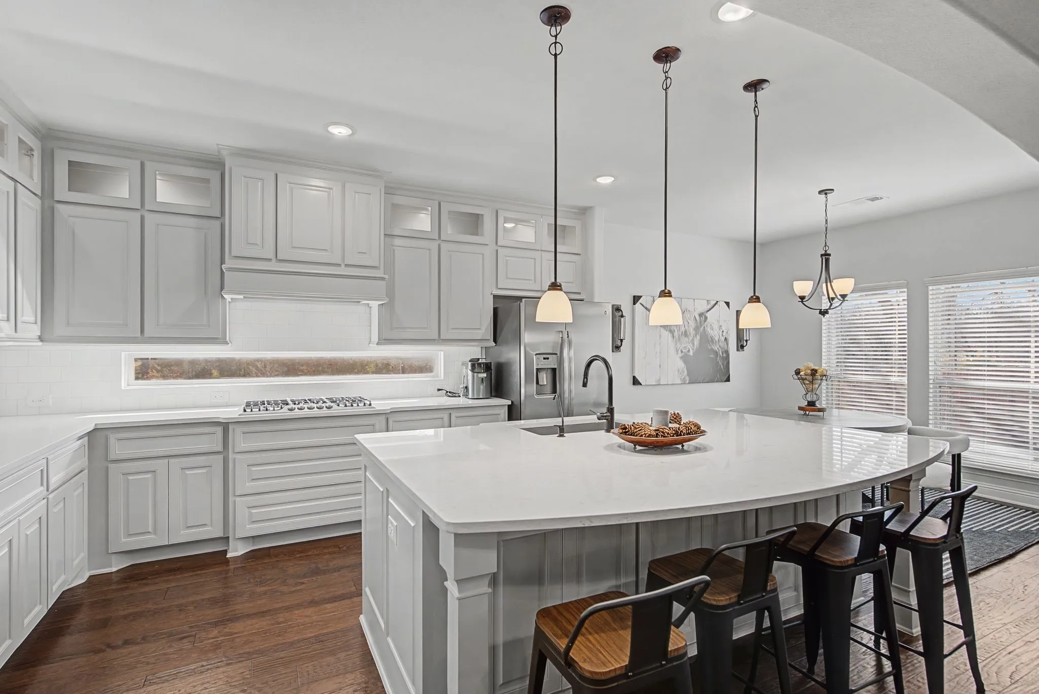 Kitchen featuring a kitchen bar, an island with sink, dark wood-type flooring, and glass insert cabinets