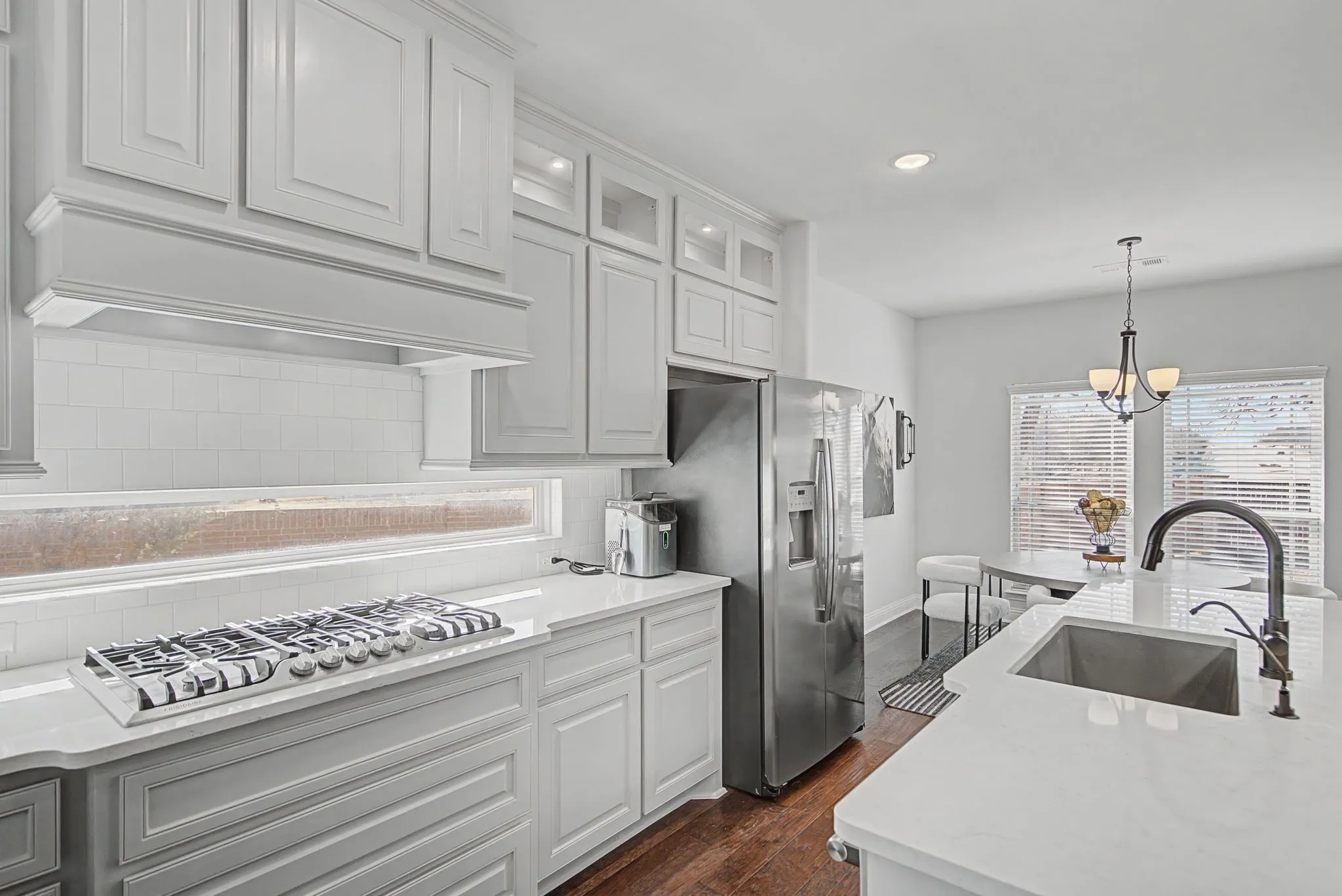 Kitchen with light stone countertops, decorative backsplash, dark wood-style flooring, stainless steel appliances, and glass fronted cabinets
