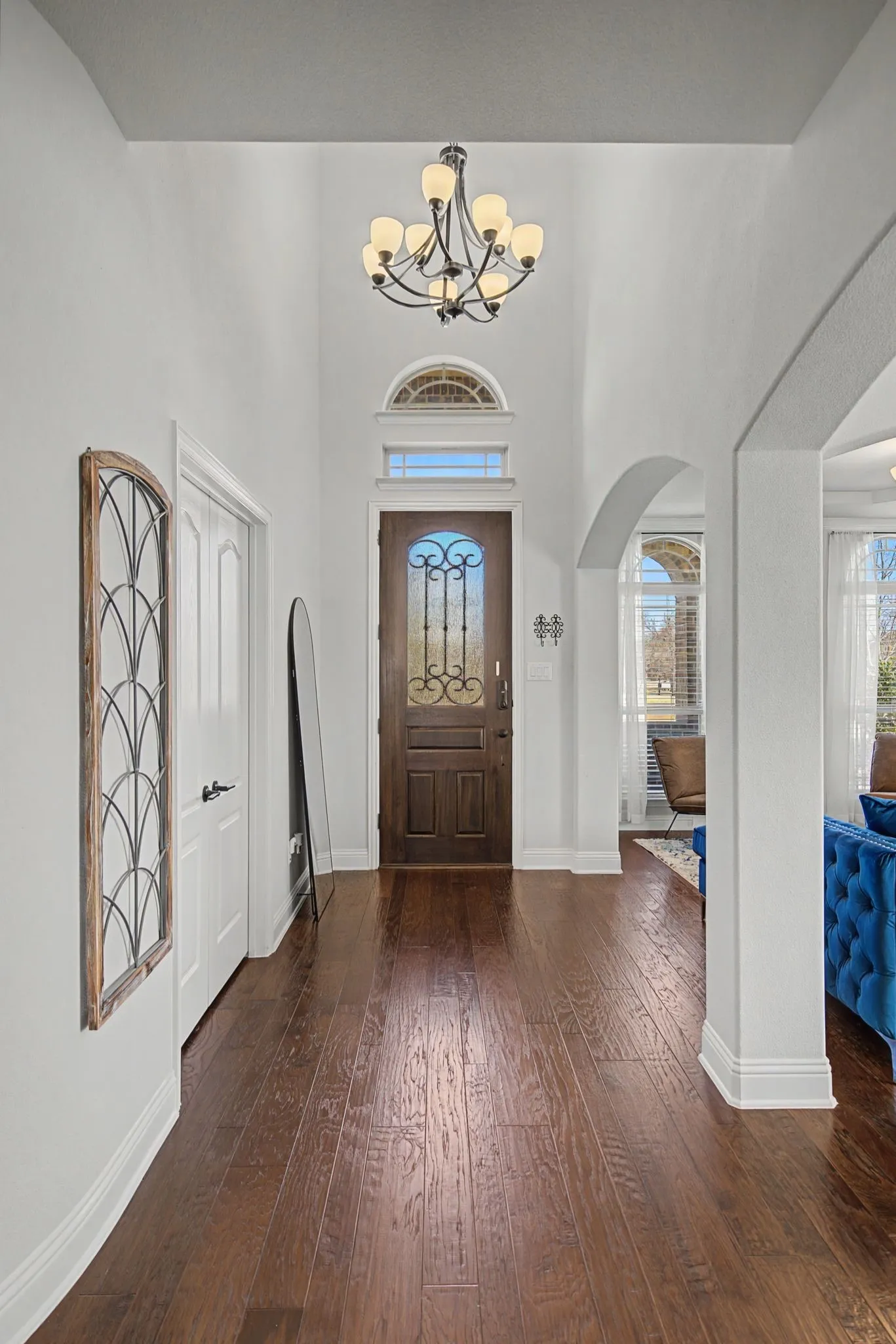 Foyer featuring dark wood-type flooring, a chandelier, a high ceiling, arched walkways, and plenty of natural light