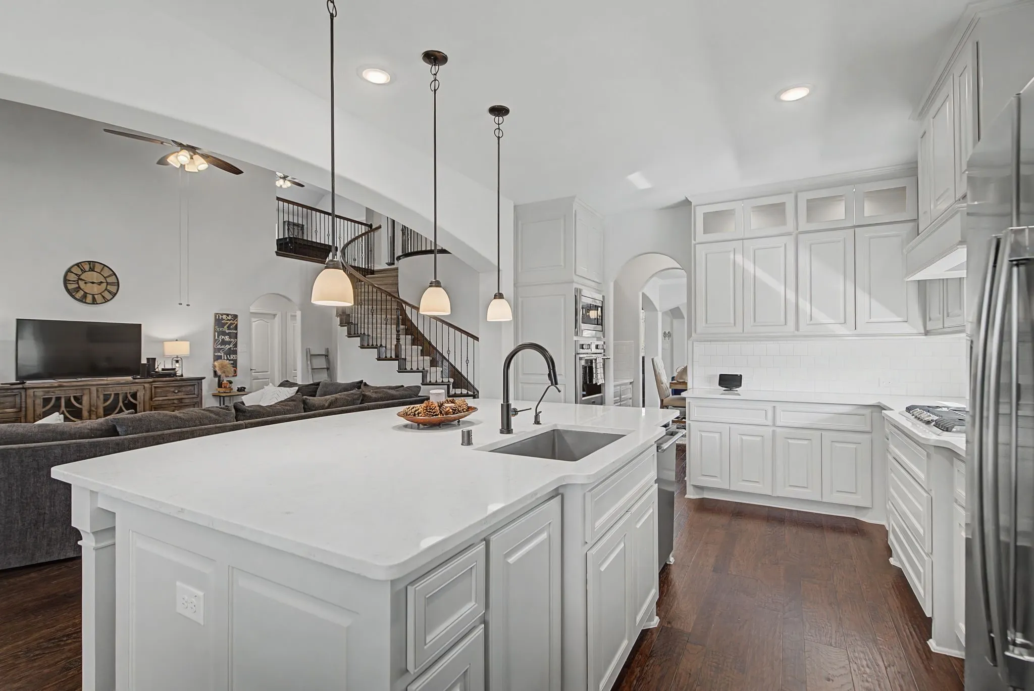 Kitchen featuring arched walkways, hanging light fixtures, open floor plan, and a center island with sink