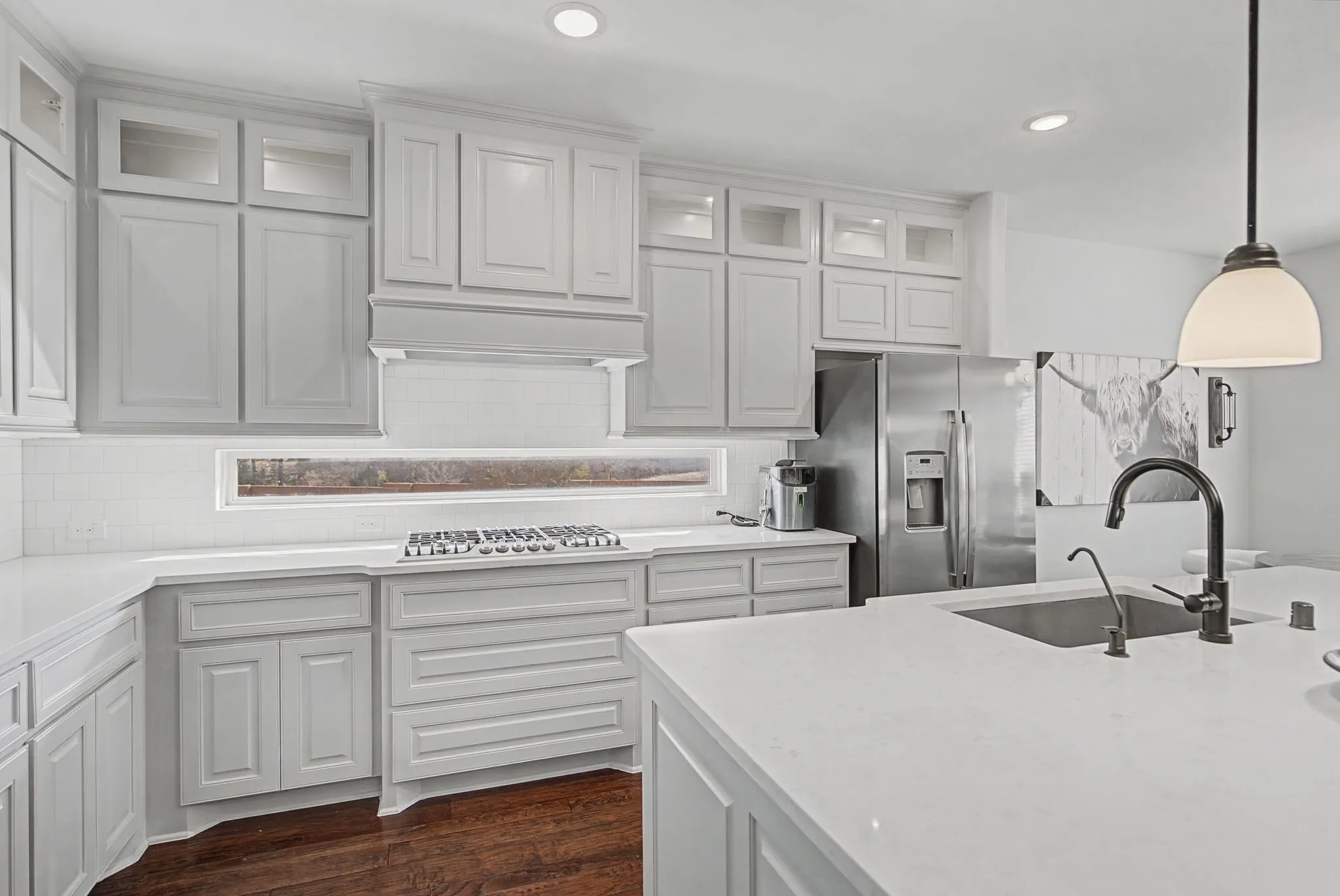 Kitchen featuring decorative light fixtures, stainless steel appliances, decorative backsplash, glass insert cabinets, and light stone counters
