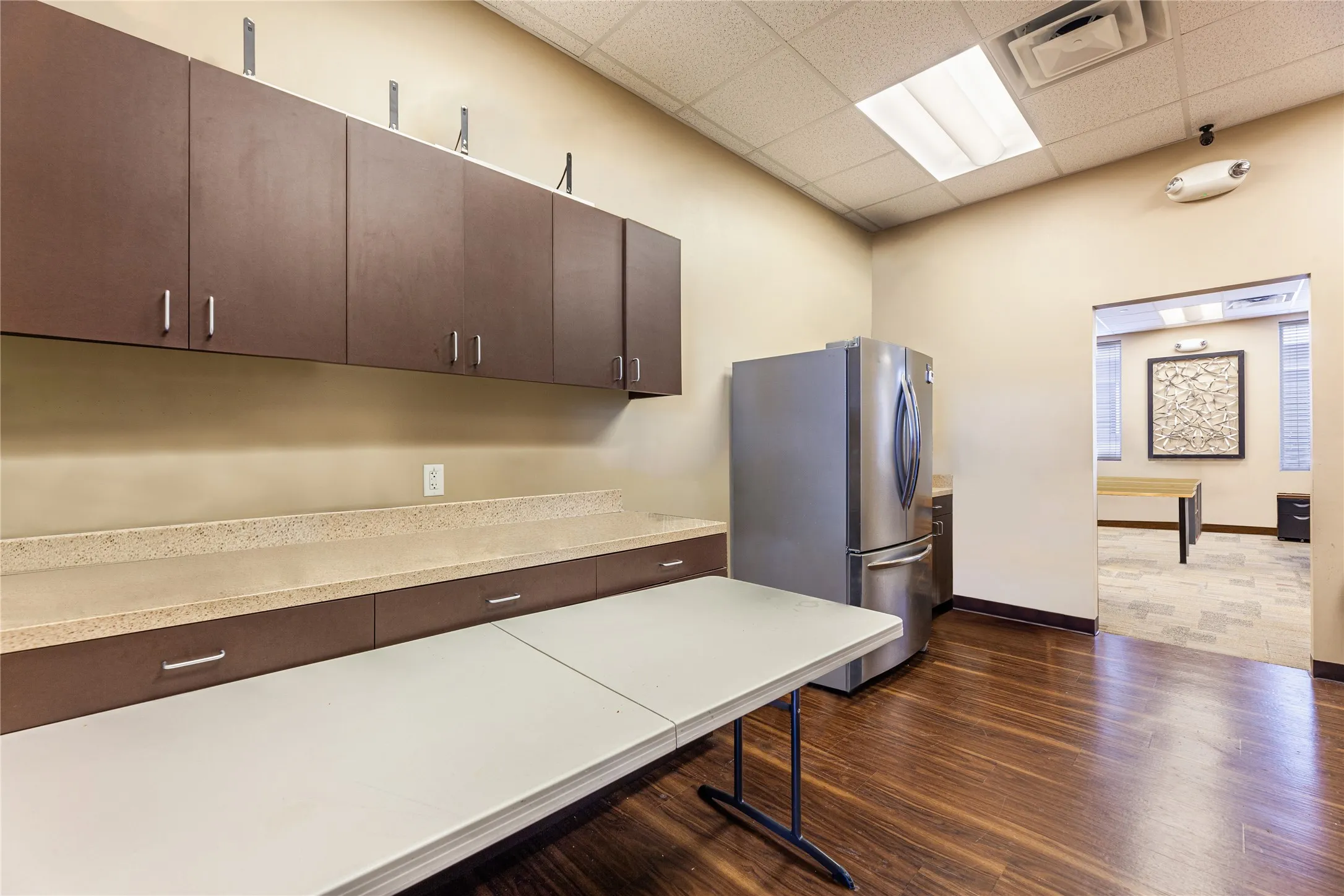 Kitchen featuring dark brown cabinets, stainless steel refrigerator, a drop ceiling, and dark hardwood / wood-style flooring
