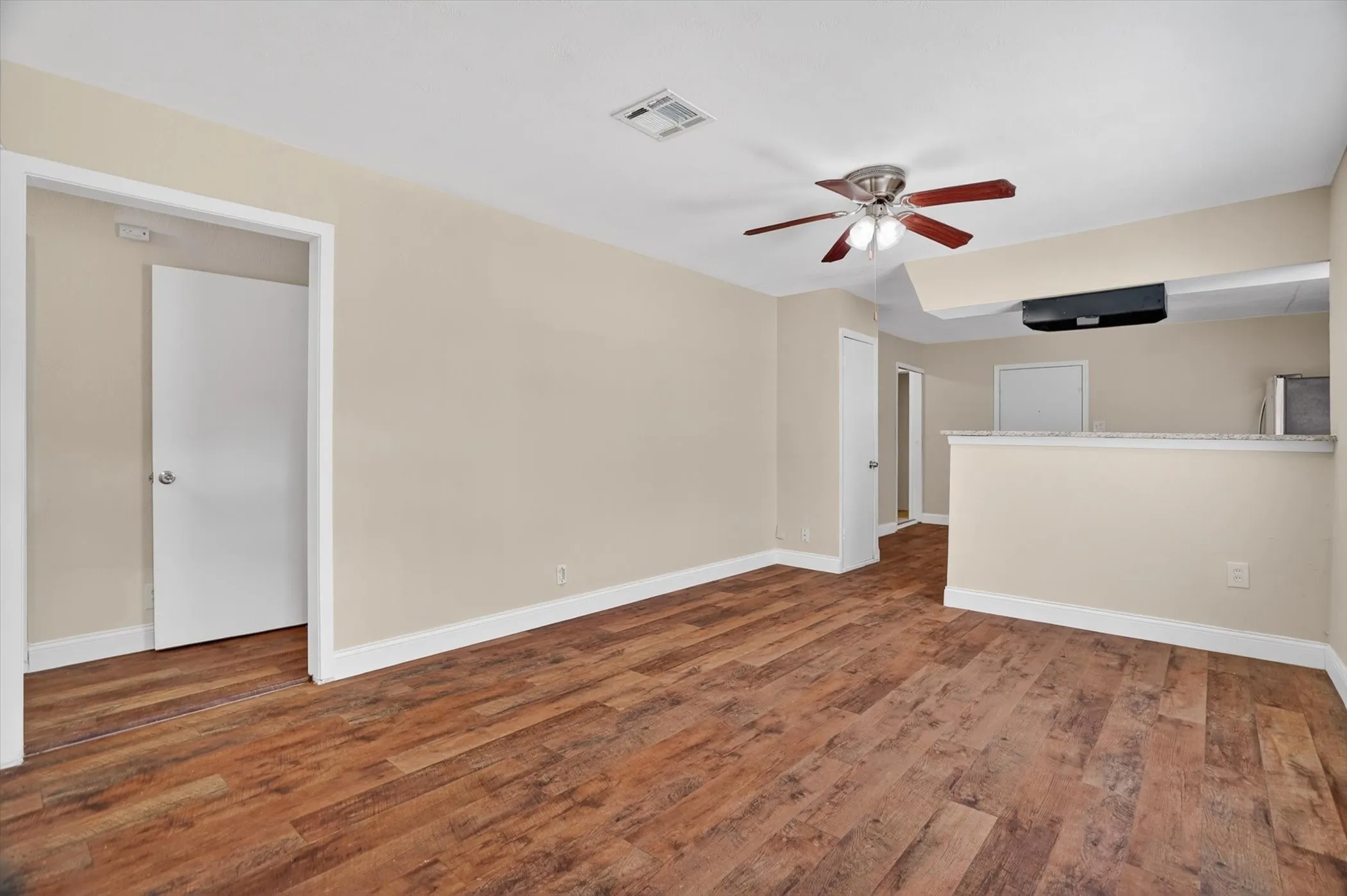 Spacious living area featuring wood-finish flooring and a ceiling fan with light fixture