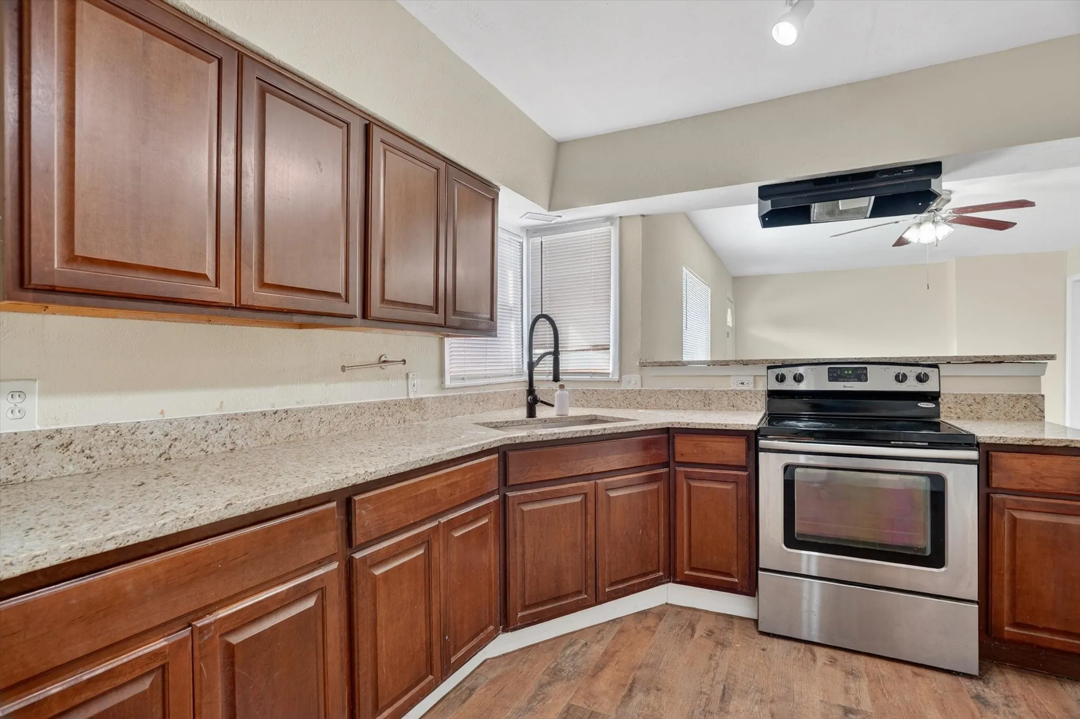 Full kitchen featuring dark wood cabinetry, light speckled countertops, a stainless steel electric range, and wood-finish flooring