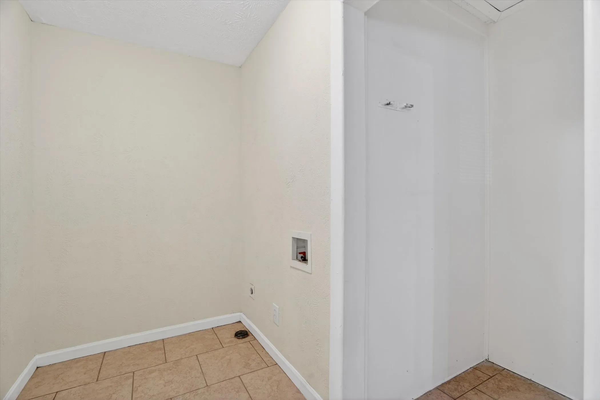 Dedicated laundry area featuring ceramic tile flooring, neutral wall paint, and utility hookups