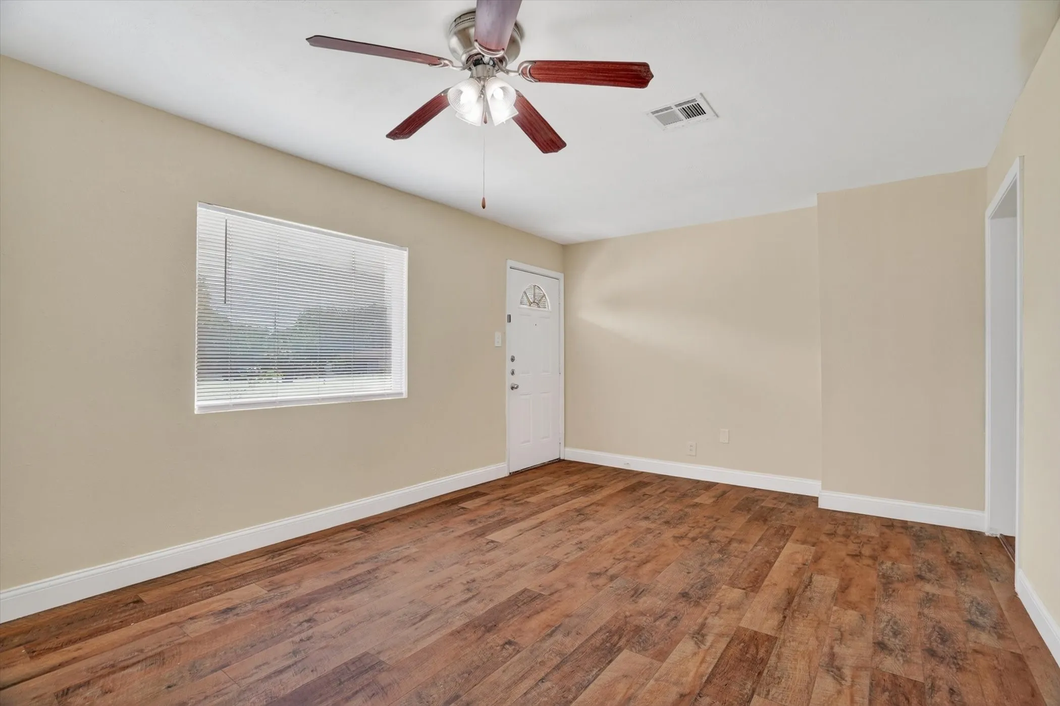 Expansive room with wood-finish flooring, neutral-toned walls, and white baseboards