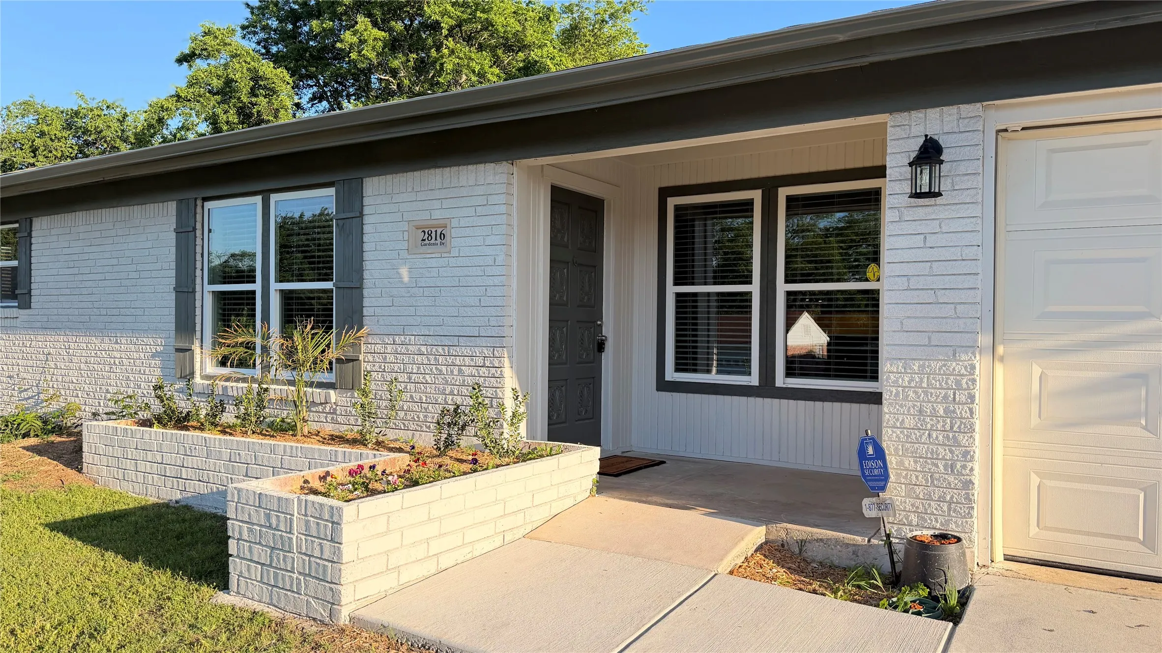 Exterior featuring painted brick and siding, a concrete walkway, and a white garage door