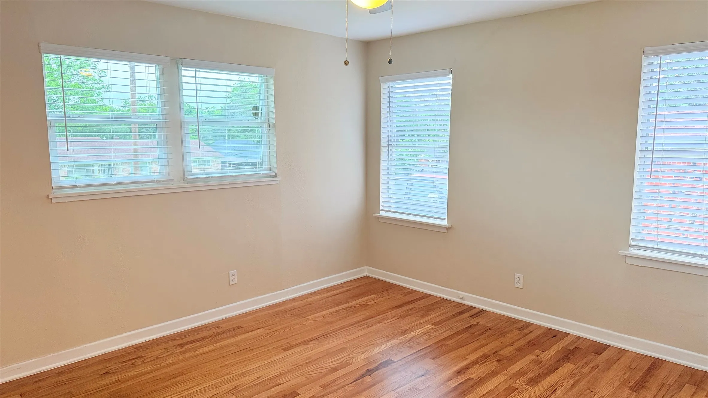 Room featuring wood-finish flooring, light neutral-toned walls, and white trim