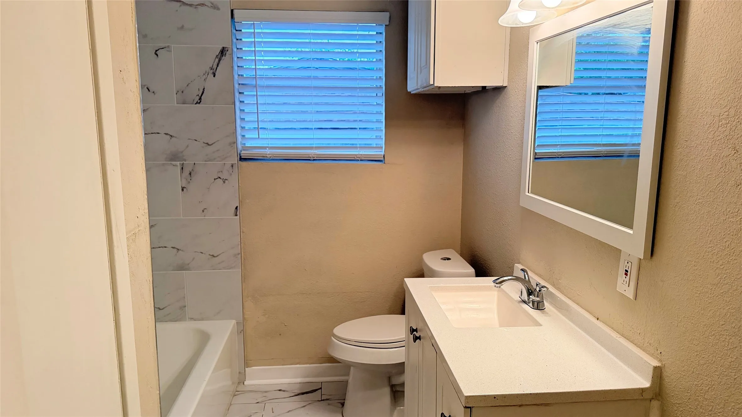 Bathroom featuring a white vanity with integrated sink, chrome faucet, and a wall-mounted mirror