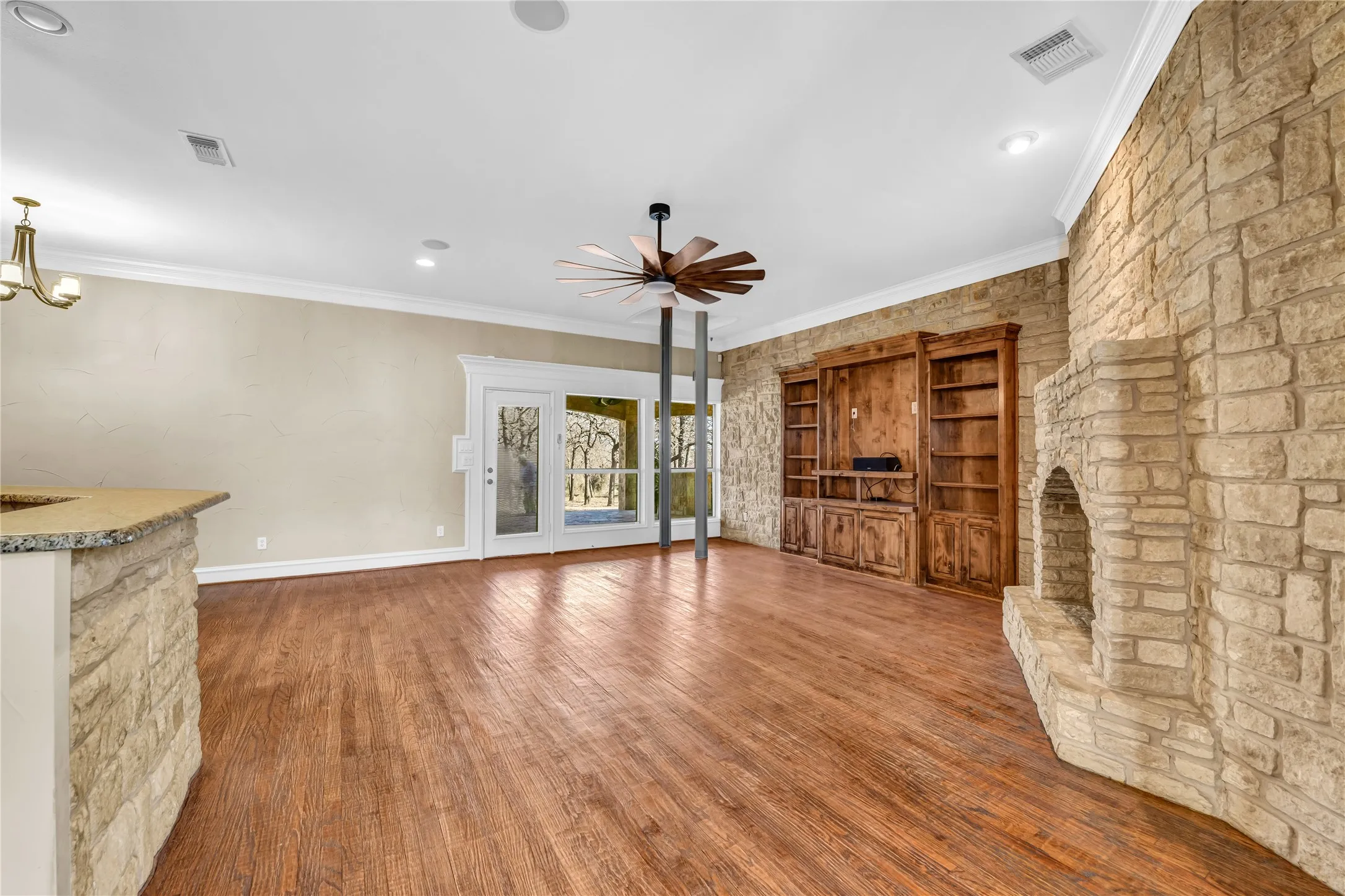 Lining room  wood finished floors,  fireplace, ceiling fan, and hanging lights