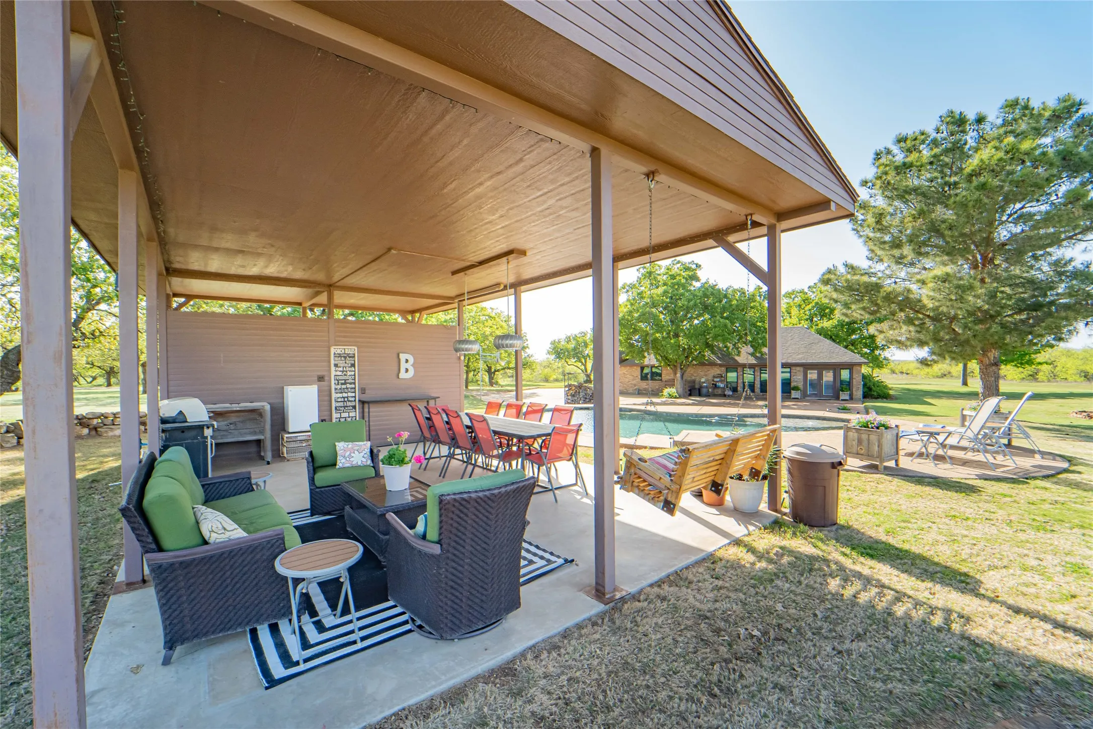 Covered option for outdoor entertaining, adjacent to a sparkling inground pool and stone firepit area-