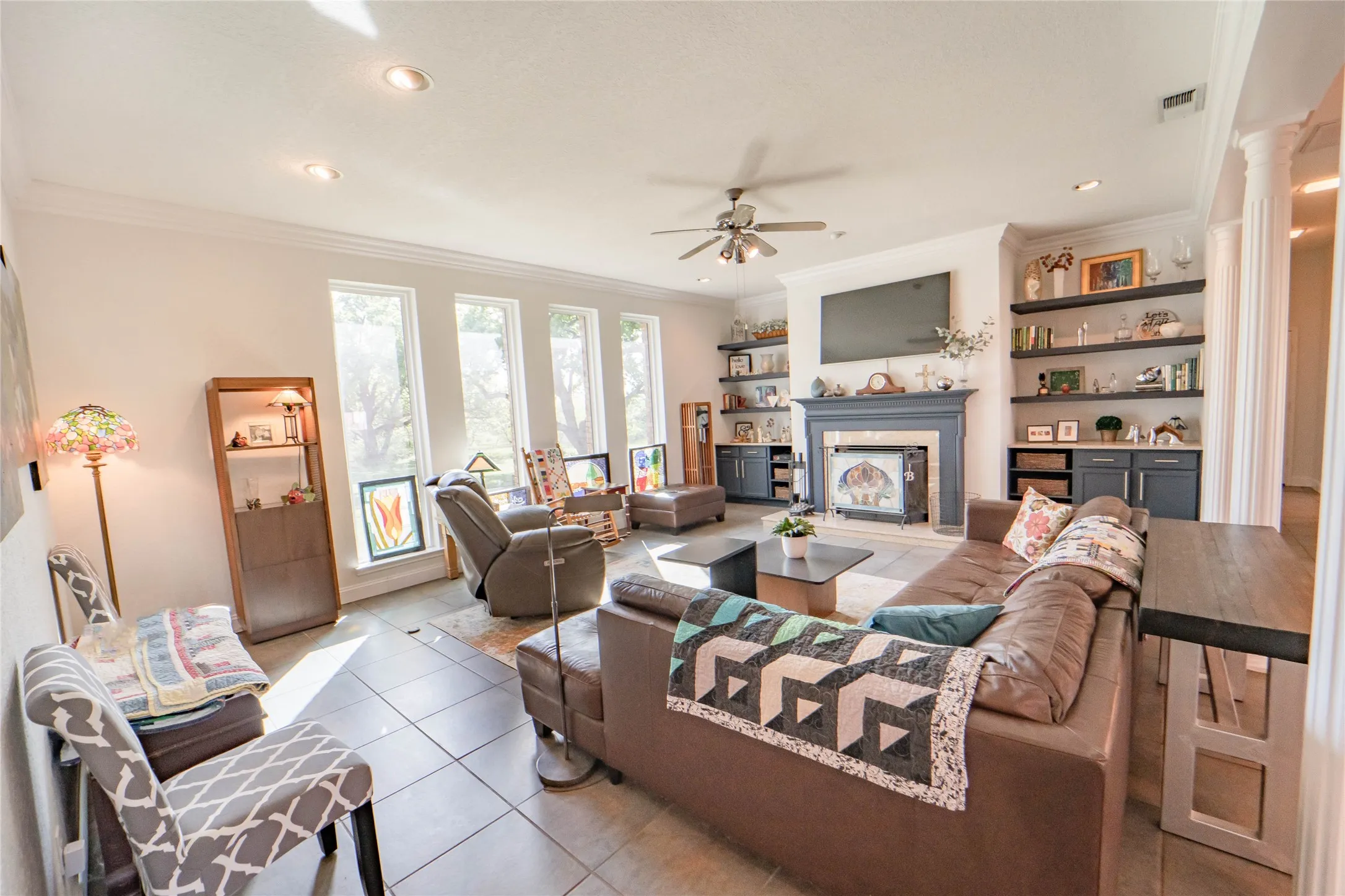 Large living area featuring a wood burning fireplace, custom built-ins, recessed lighting, great natural lighting with views of the wooded outdoors.