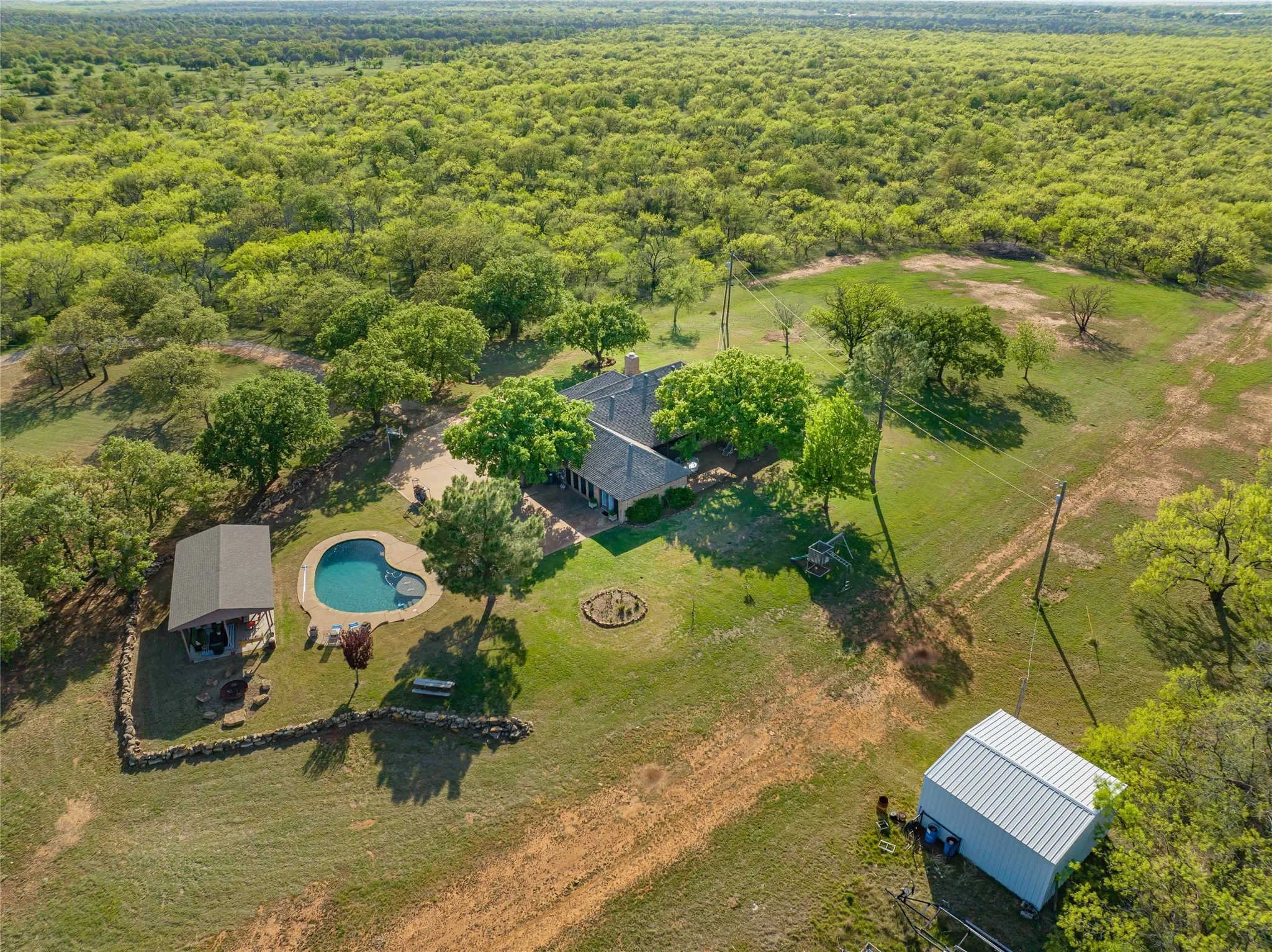 Aerial view showing outdoor living options-excellent location for relaxing in the pool on hot summer days, warming by the firepit on chilly evenings and grilling under the covered pavilion year round!