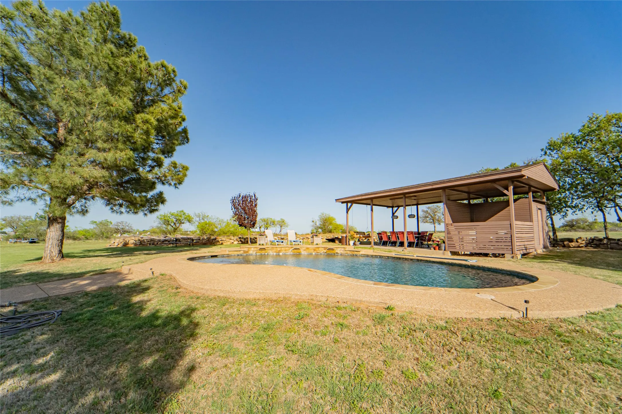 Private inground pool with water feature-storage for pool equipment located conveniently inside covered pavilion storage area-