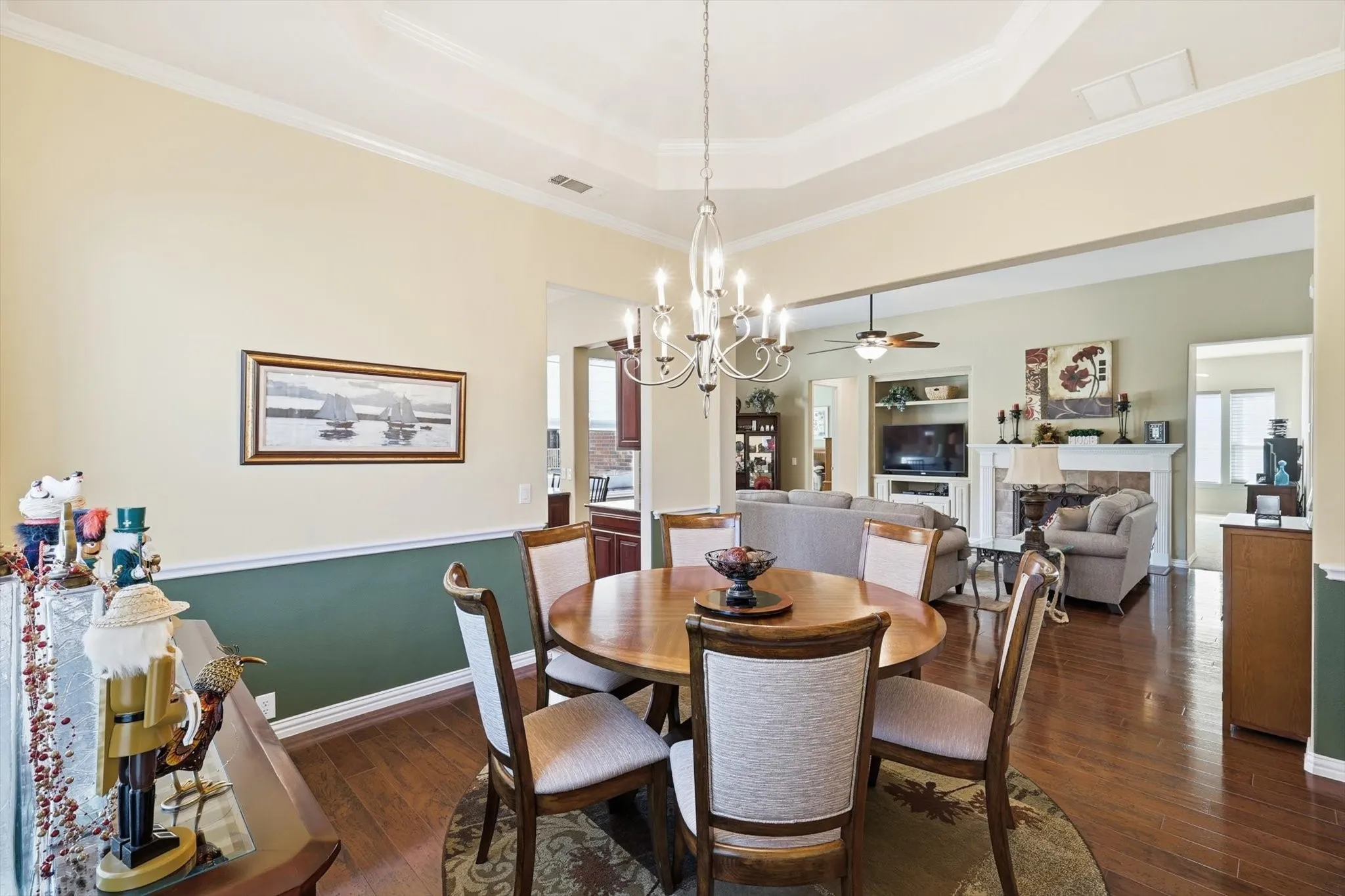 Dining room with dark wood-style floors, crown molding, a raised ceiling and chair rail opens to Living Room