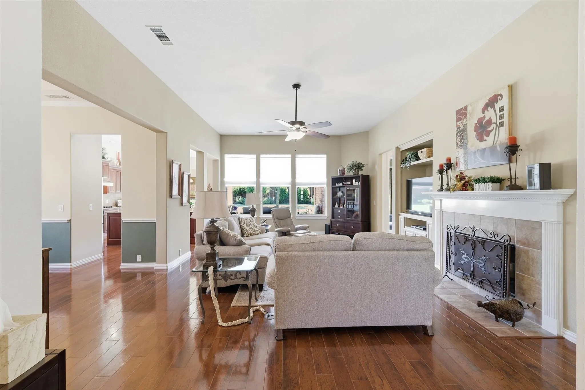 Living room featuring a fireplace, a ceiling fan, and dark wood-style floors