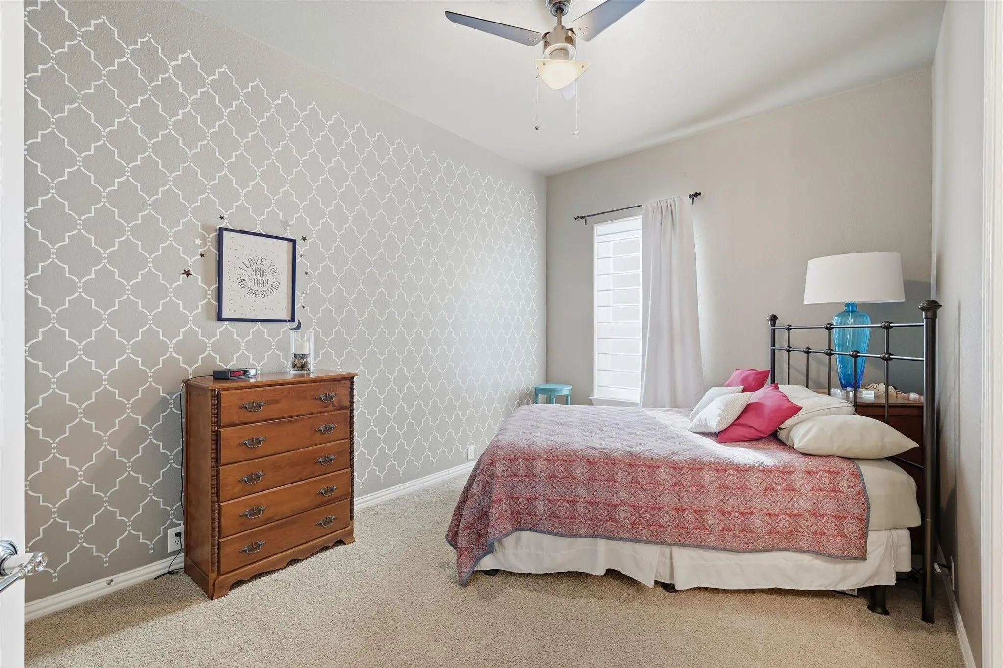 Bedroom with light colored carpet, wallpapered walls, and a ceiling fan