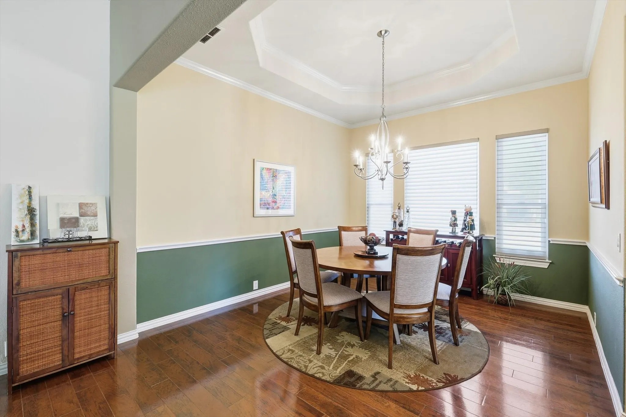 Dining area with crown molding, a raised ceiling, dark wood-style floors, and a chandelier