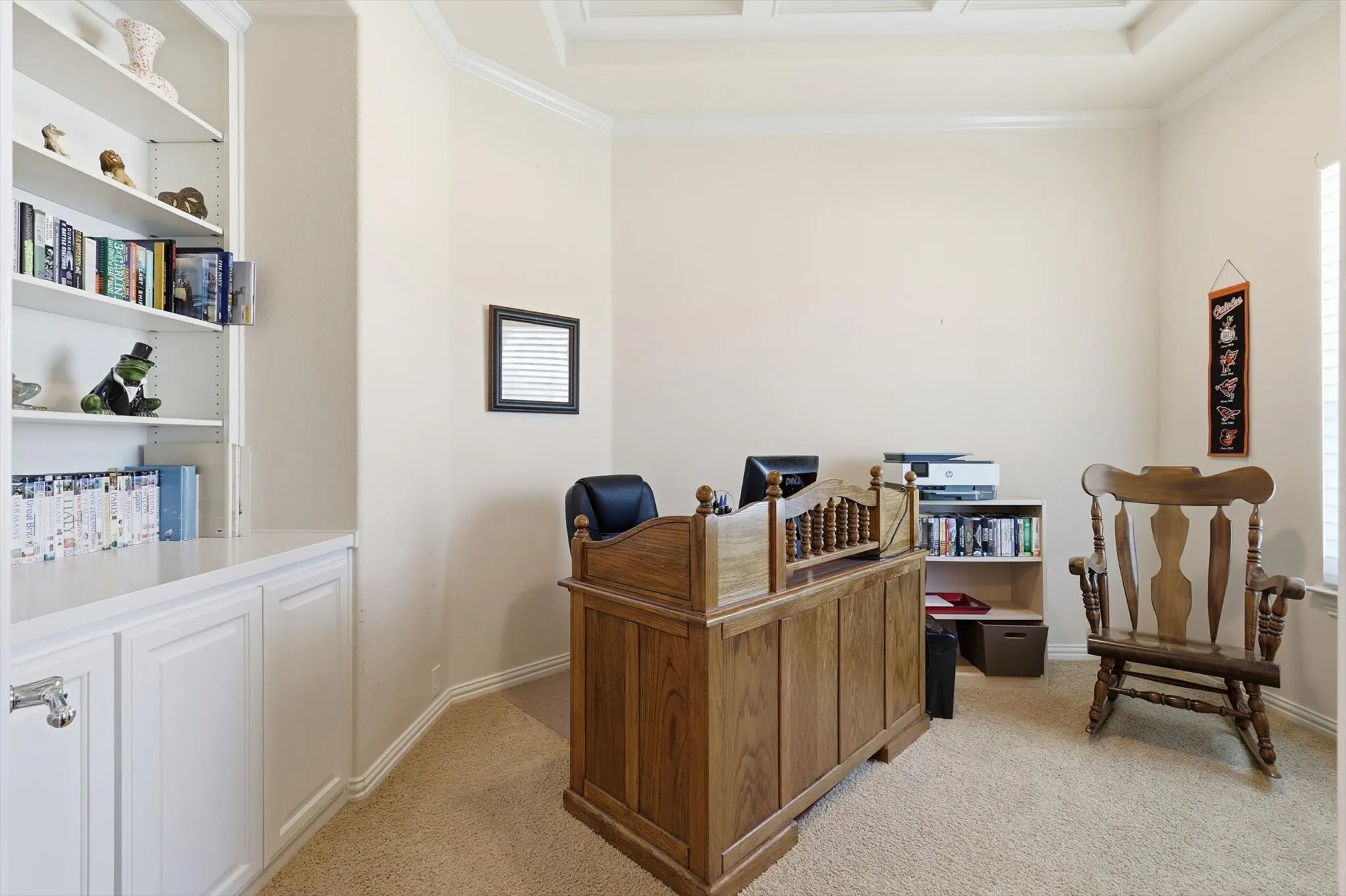 Office area with light carpet and crown molding and built in shelves and cabinet
