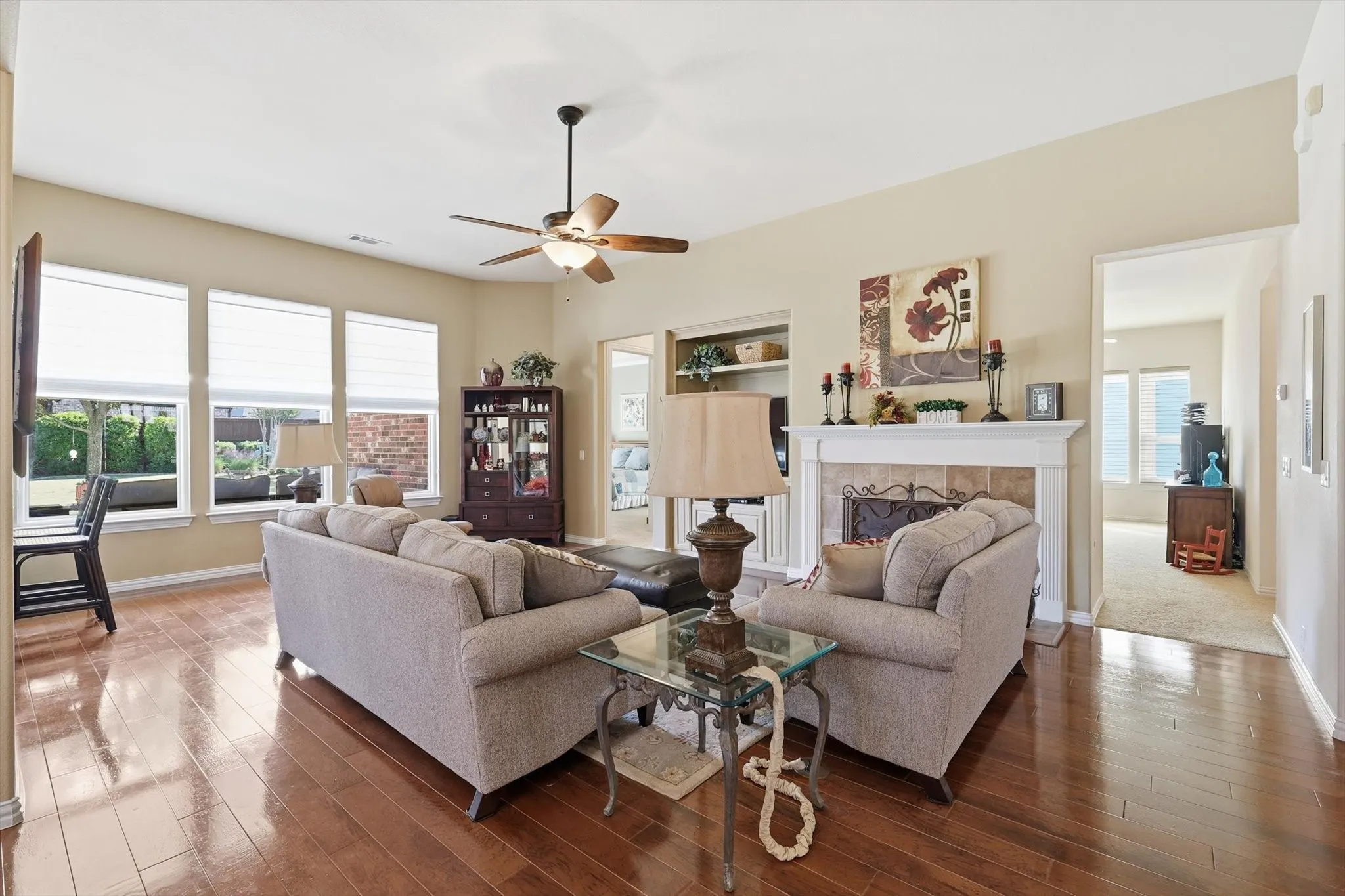 Living room with a fireplace, a ceiling fan, and hardwood / wood-style flooring