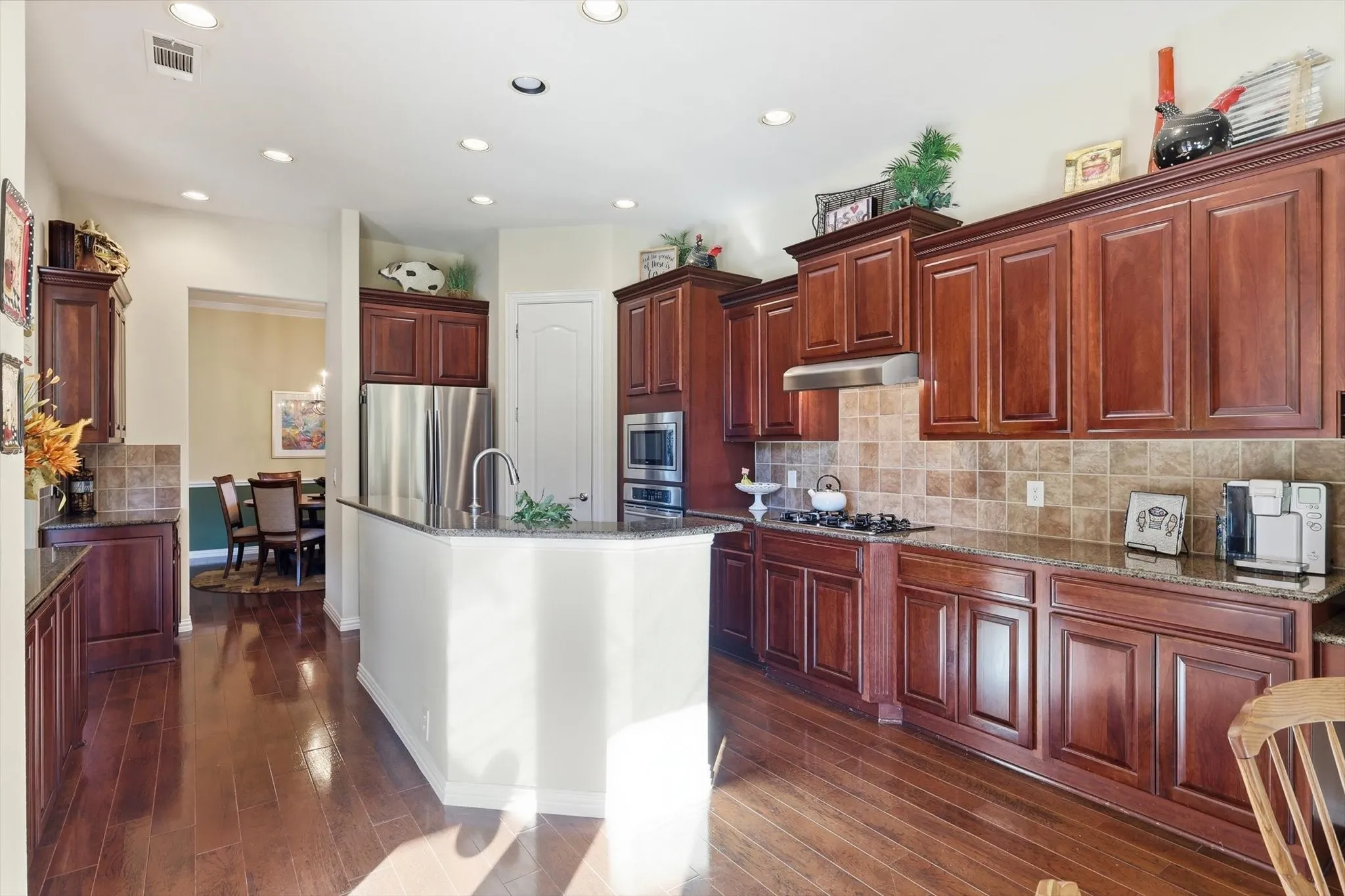 Kitchen with decorative backsplash, stainless steel appliances, under cabinet range hood, dark stone countertops, and recessed lighting