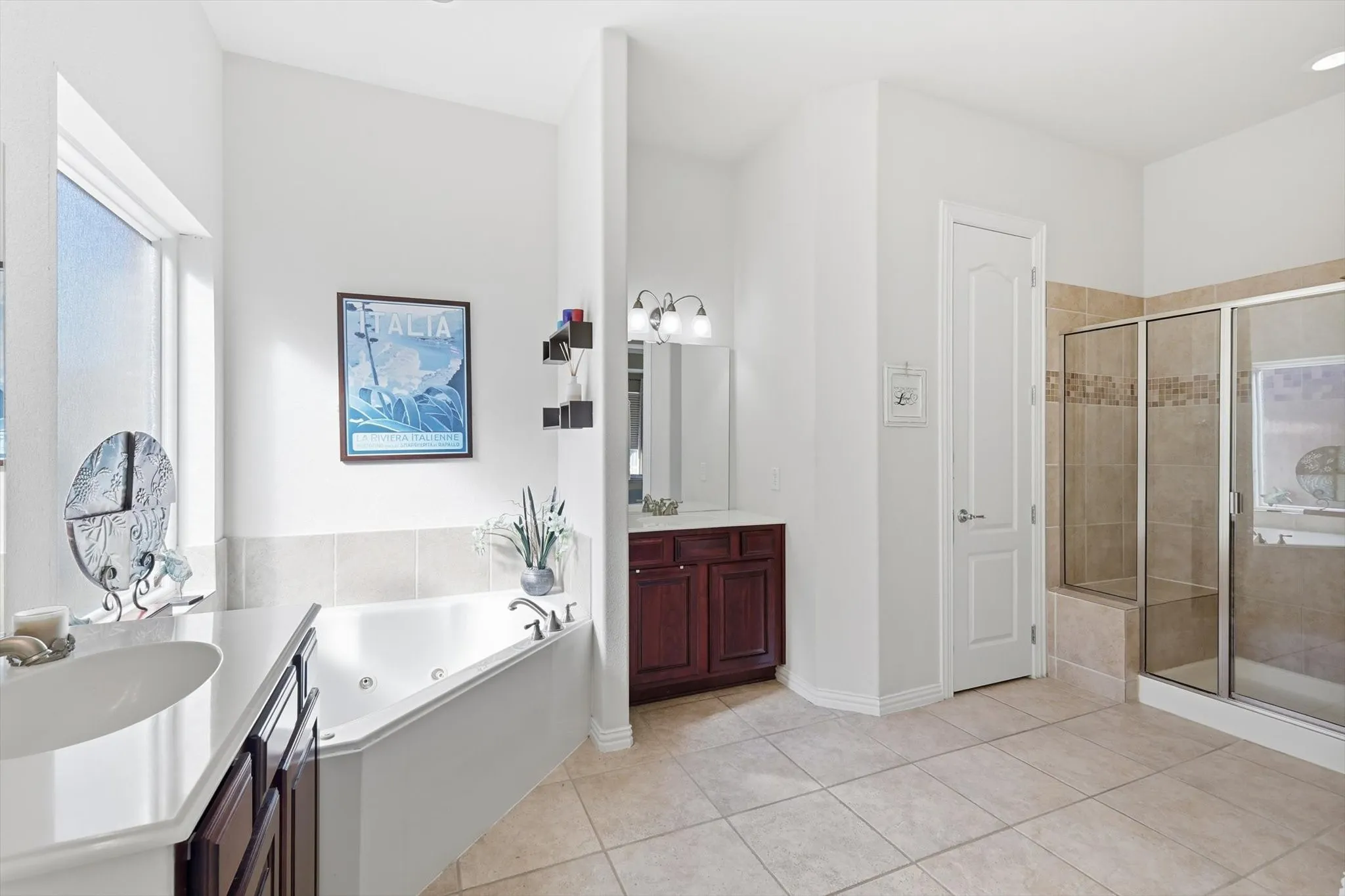 Primary bathroom featuring light tile patterned flooring, a garden bathtub with jets, and dual vanities