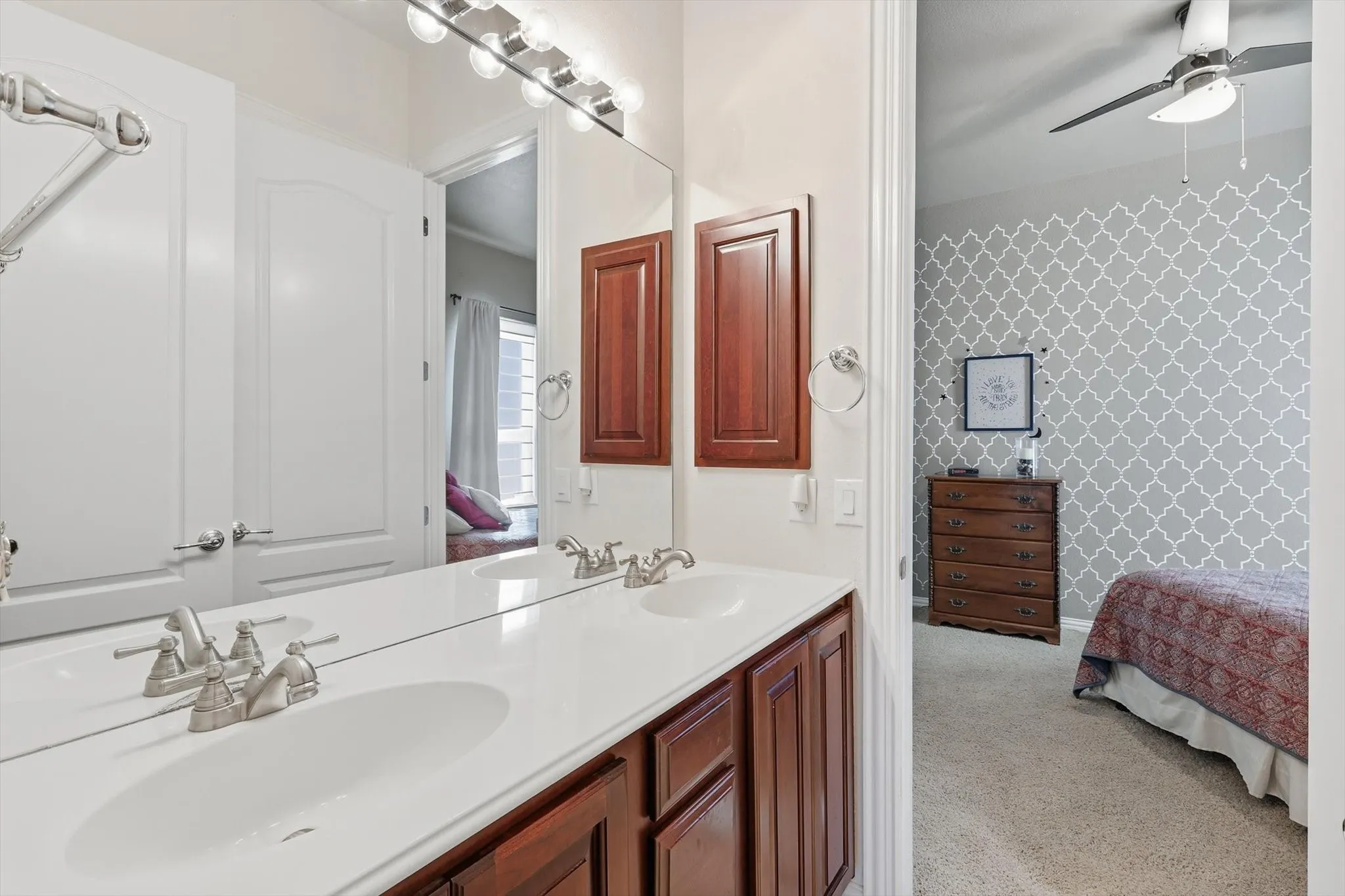 Ensuite Jack & Jill bathroom featuring double vanity, light colored carpet, and built in cabinets